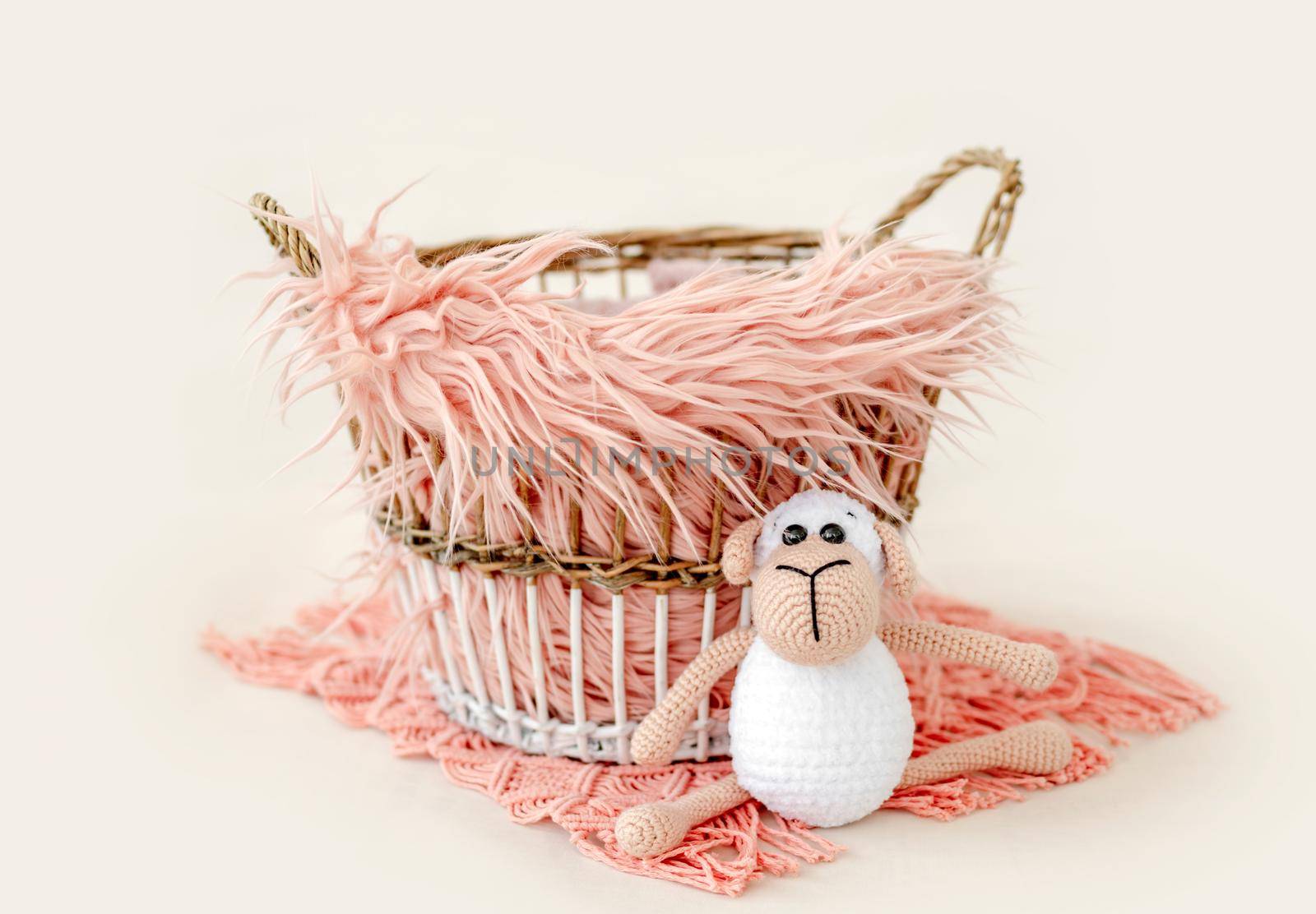 Tiny basket decor for newborn studio photoshoot filled with fur and knitted toy closeup. Infant baby handmade furniture