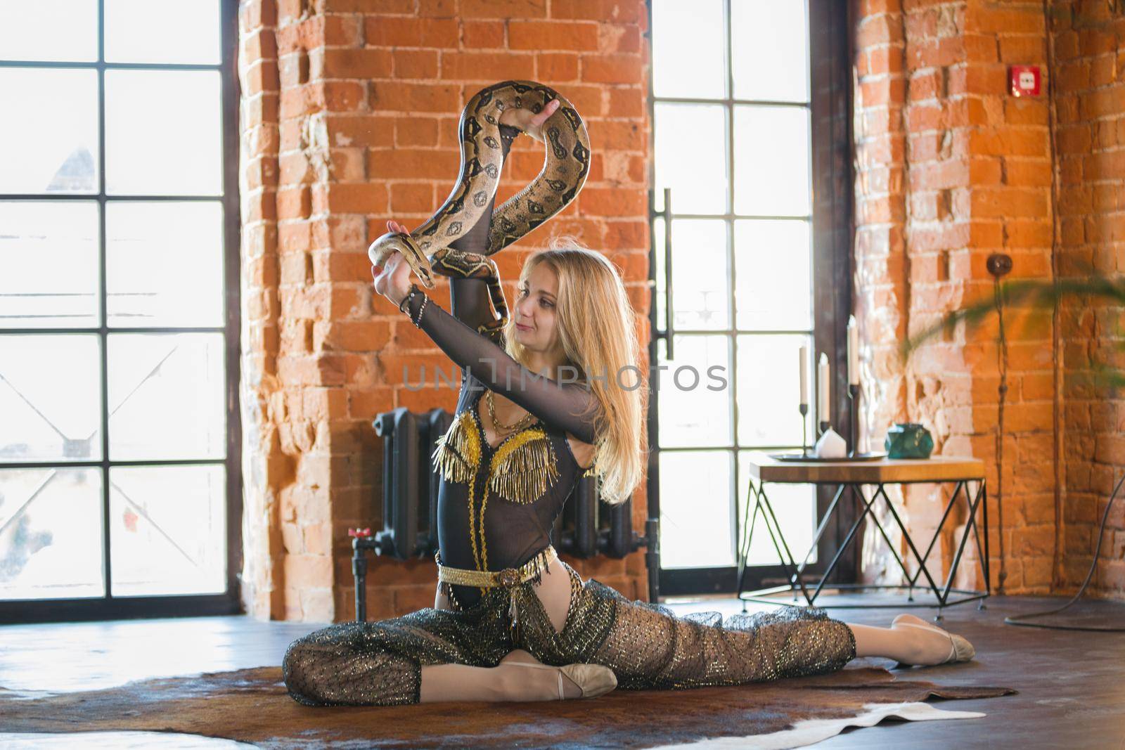 Slim young woman performing dance with a snake in studia, close up