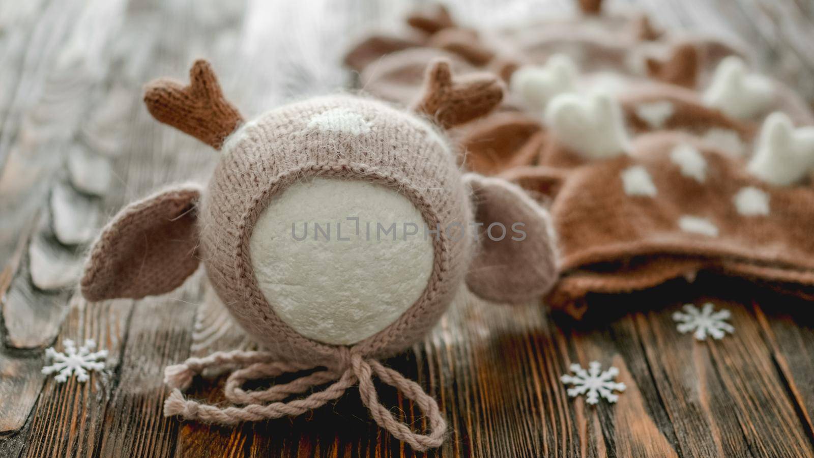 Knitted newborn hats for infant Christmas studio photoshoot on wooden background closeup. Cute baby clothes design