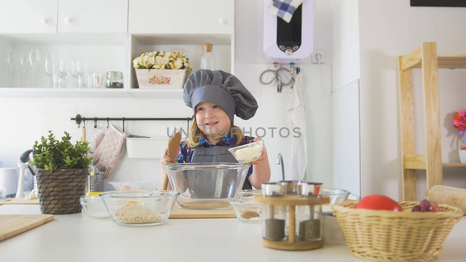 Little girl baker puts batter to the pastry dough for cooking biscuits, close up