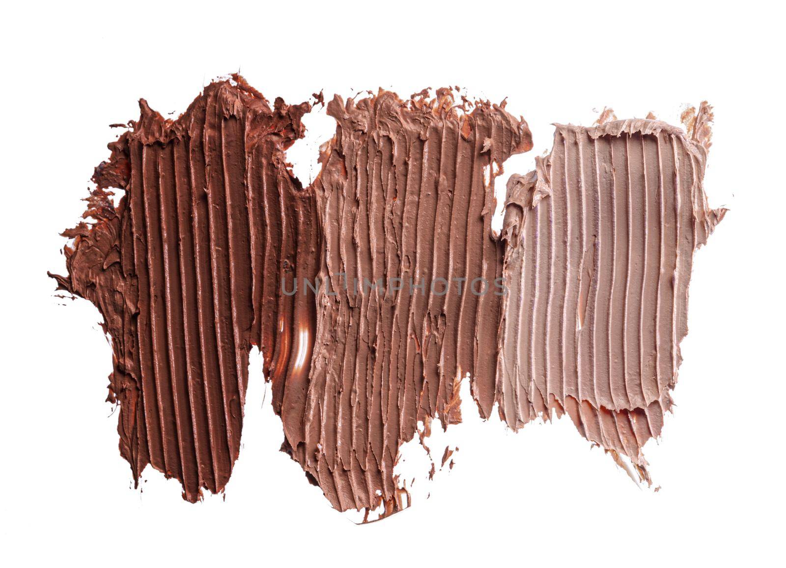 Smears of dark cream cosmetic foundation isolated on white, close up