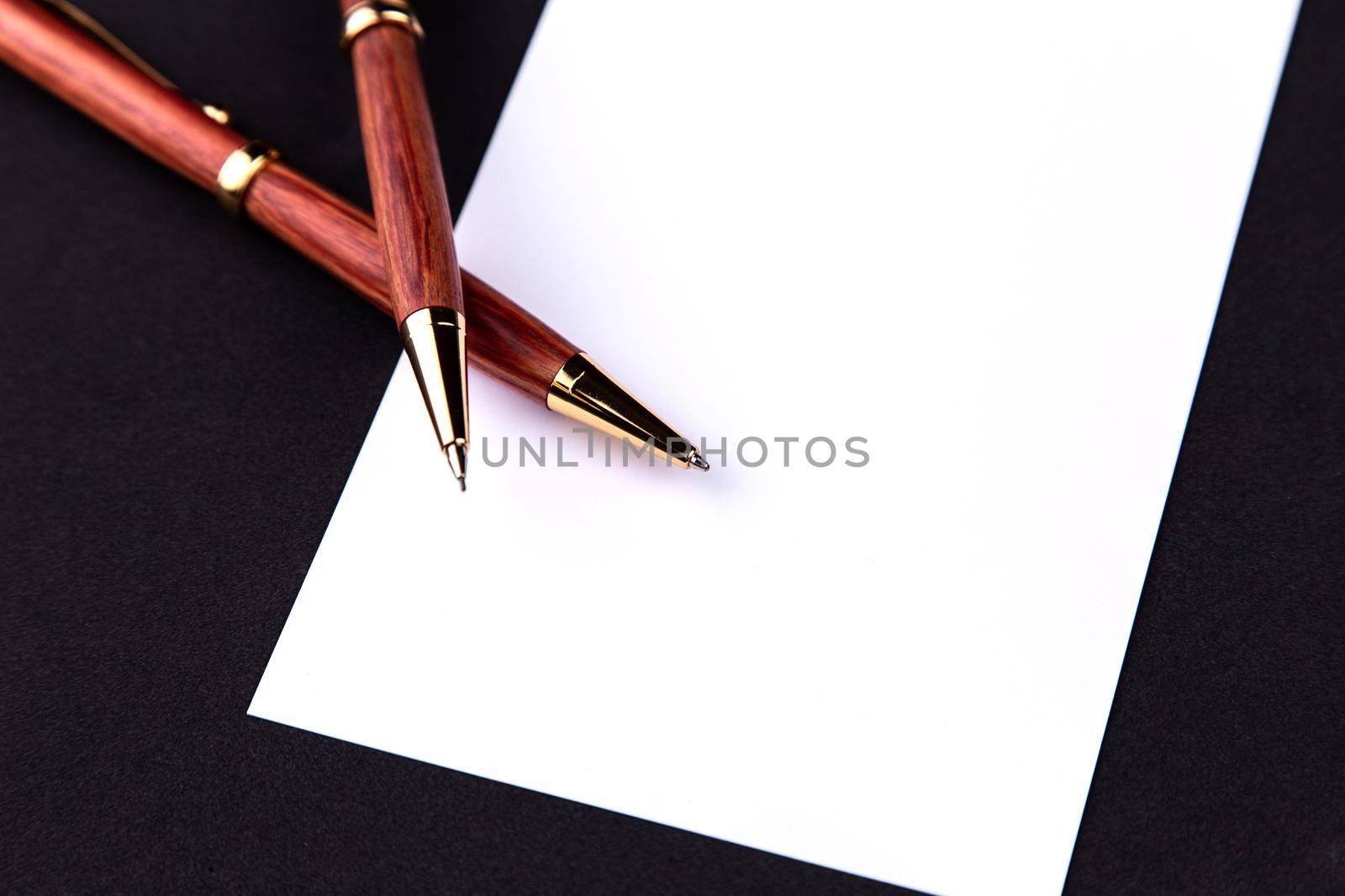 Luxury pen and mechanical pencil in wood and gold with a white sheet of paper.