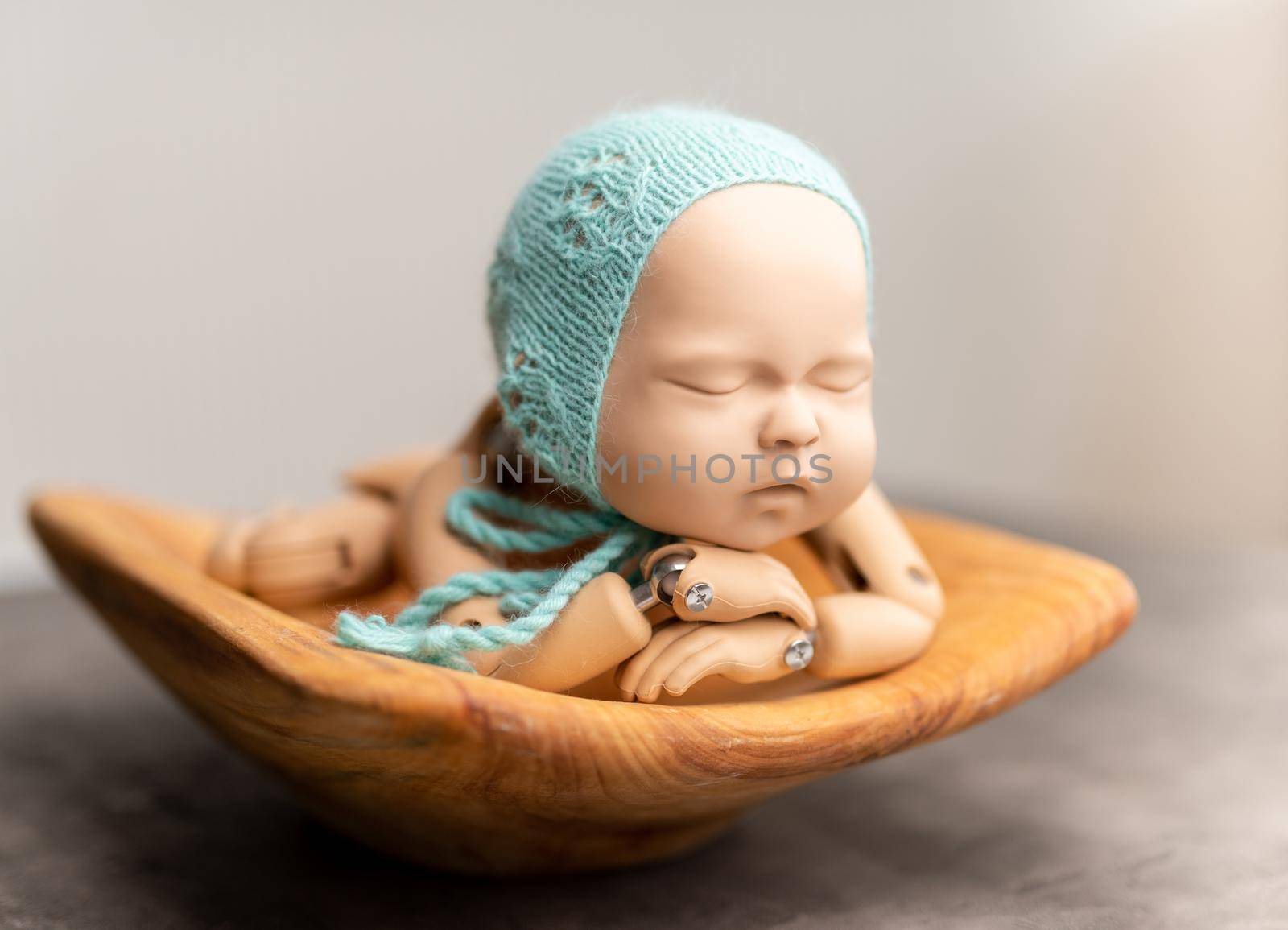 Realistic plastic figure of newborn child for photographing practice, with head on hands