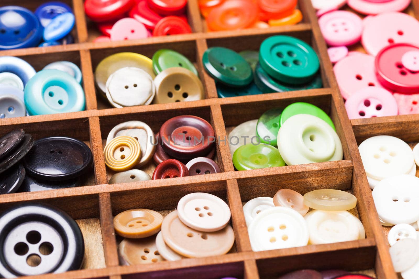 Colorful buttons in a wooden box for design