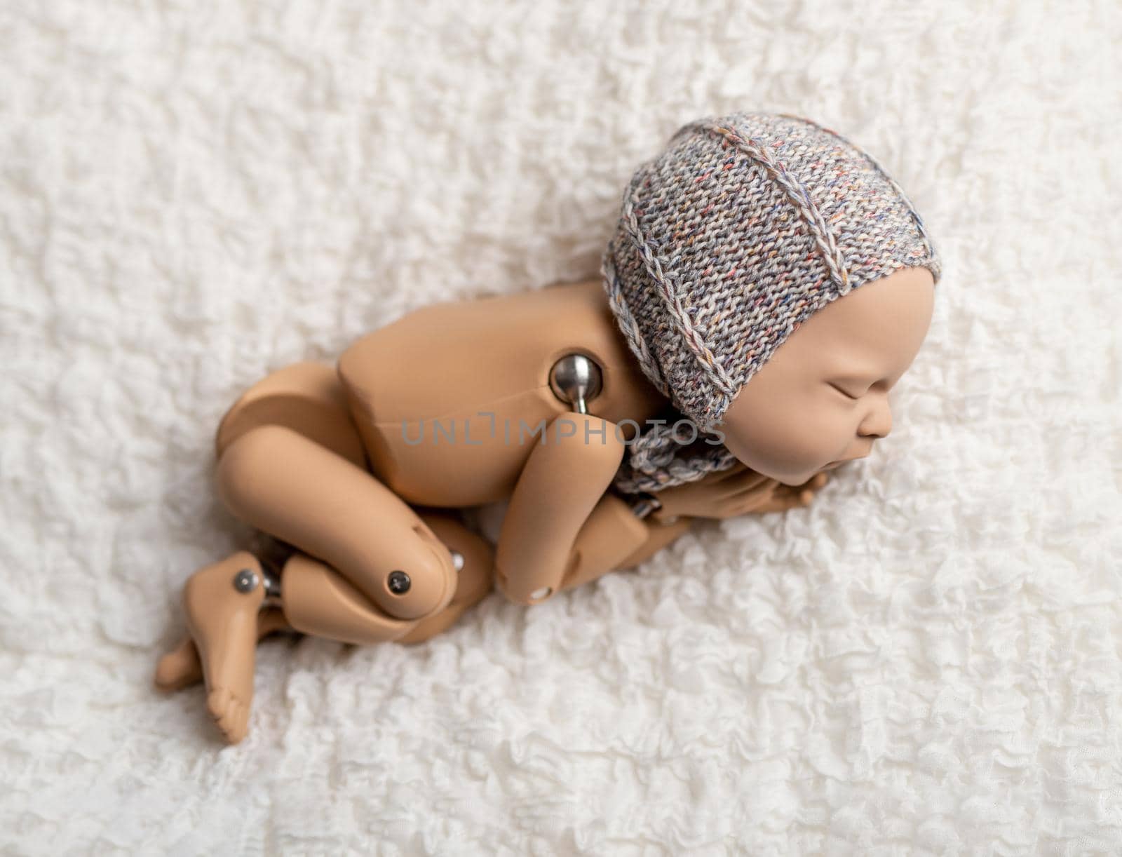 Precisely accurate mannequin of newborn in a hat for photo practicing