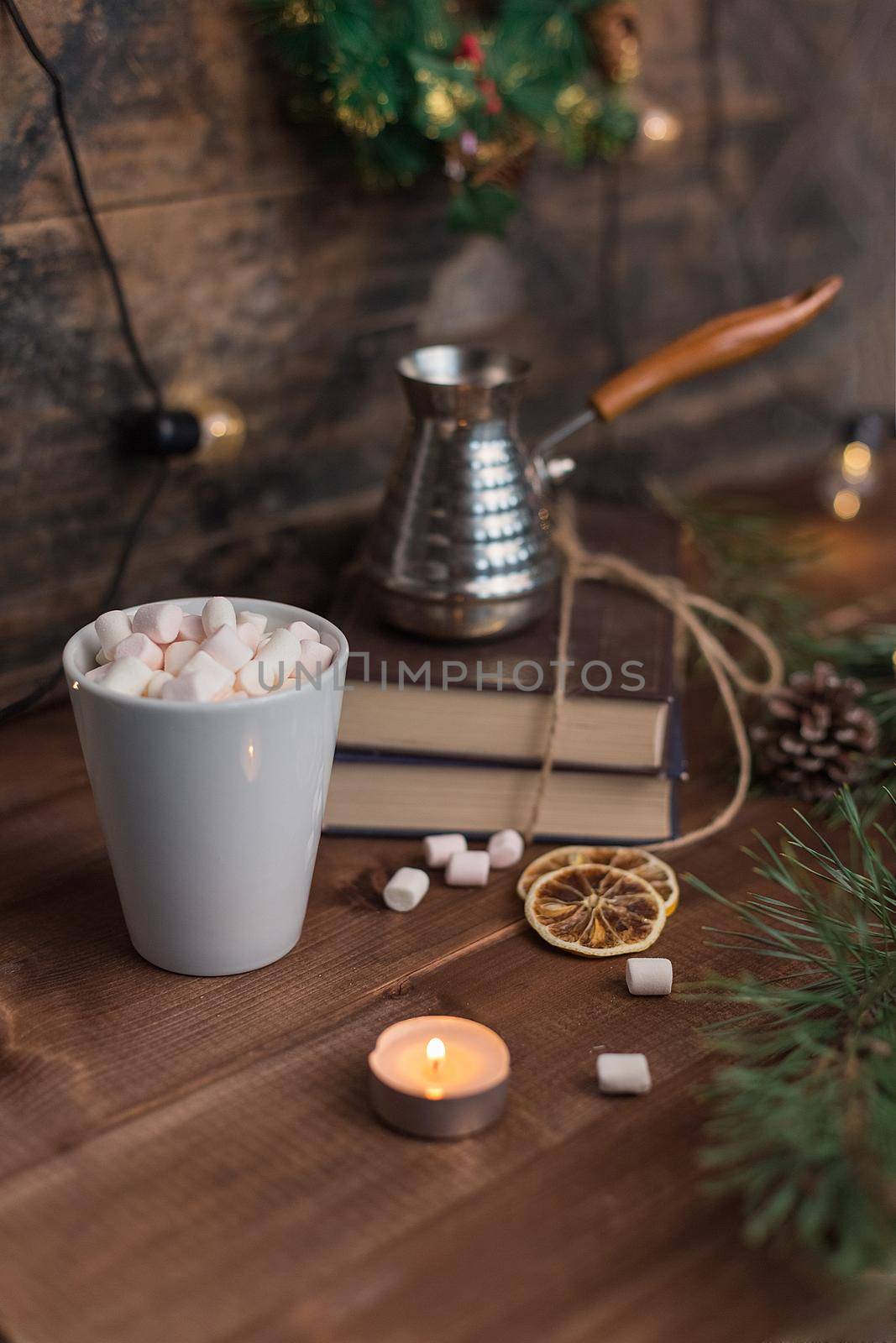 Marshmallows in a cup of cofee with turka, lighted candle on wooden background. New Year and Christmas cocept.