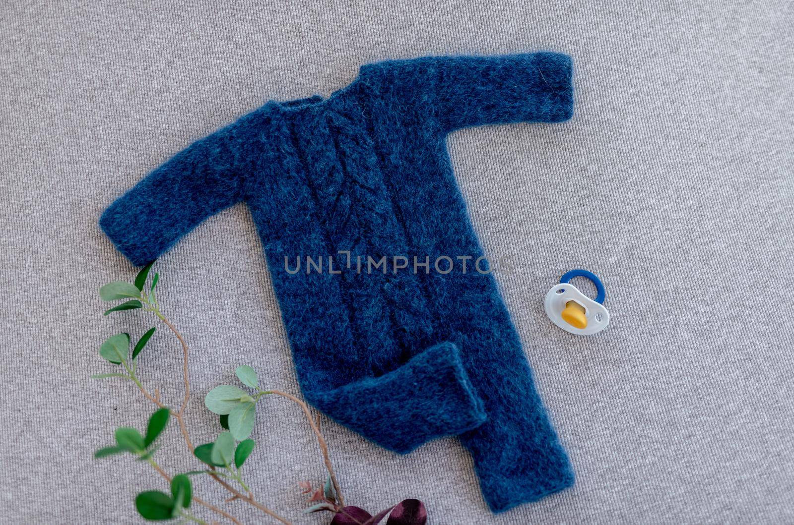 Blue knitted newborn clothes composition with plants and soother for infant baby photosession