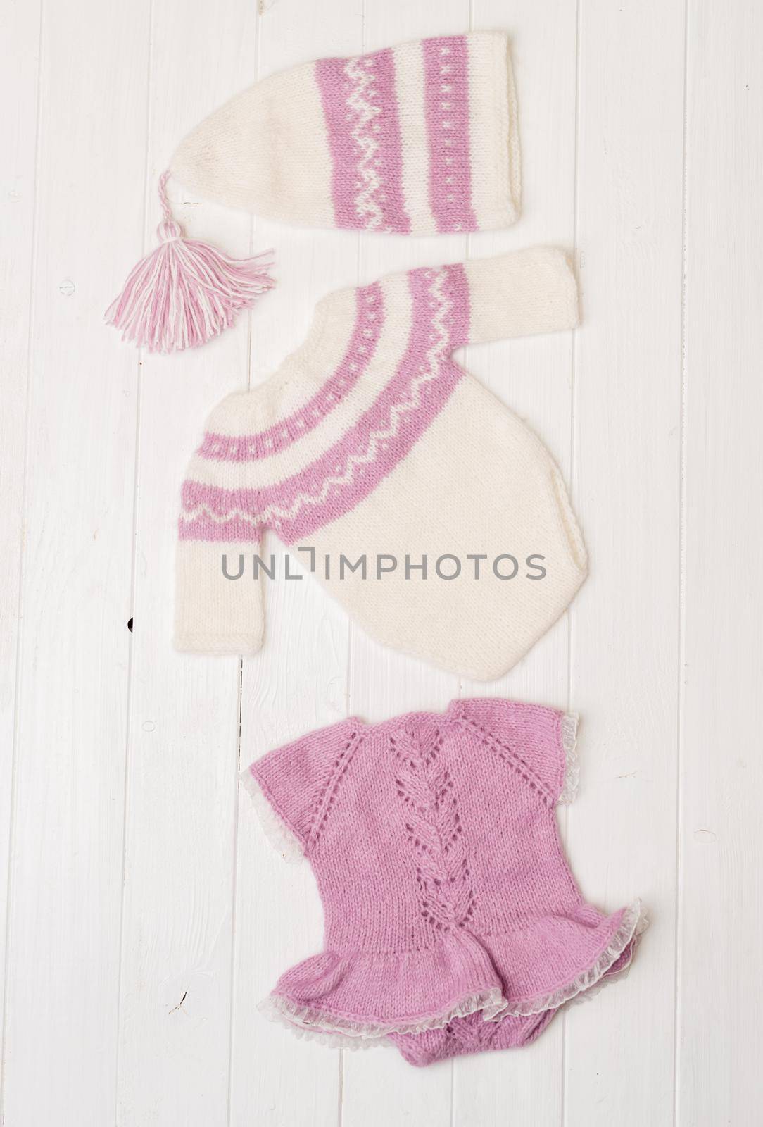 Composition of white-pink knitted suit and hat with decorations