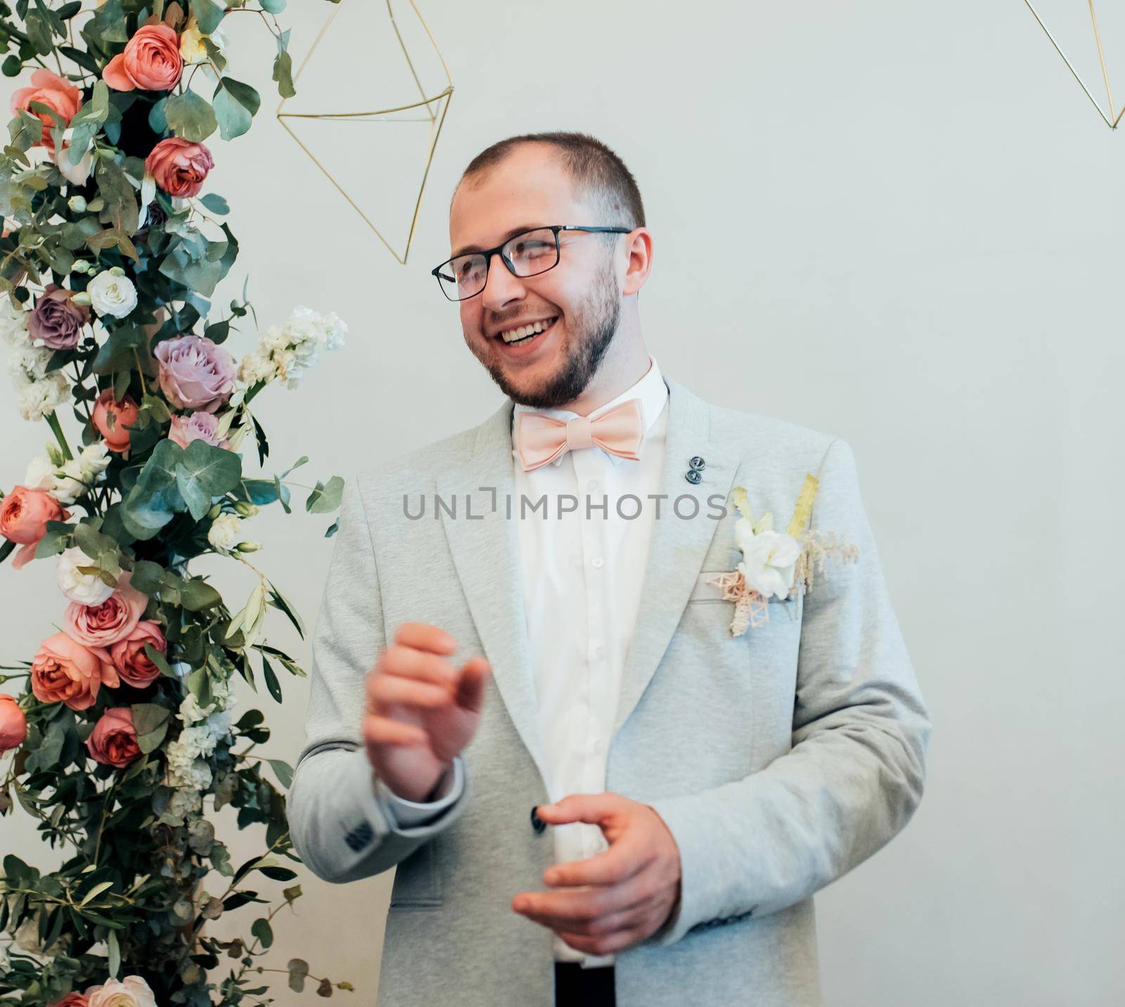 Wedding photo of emotions of a bearded groom with glasses in a gray jacket and rustic style.