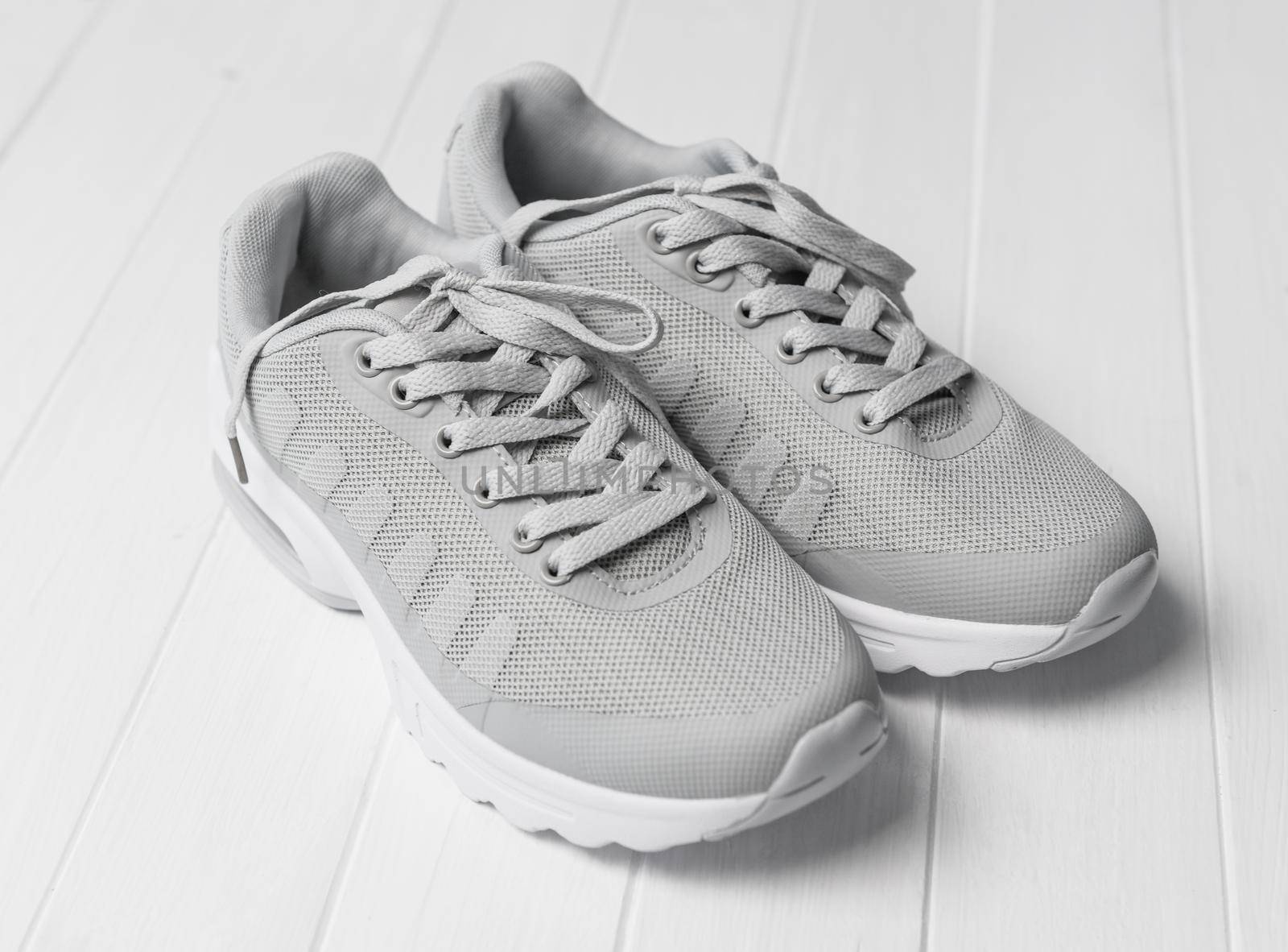 Gray cozy running shoes sitting on wood by tan4ikk1