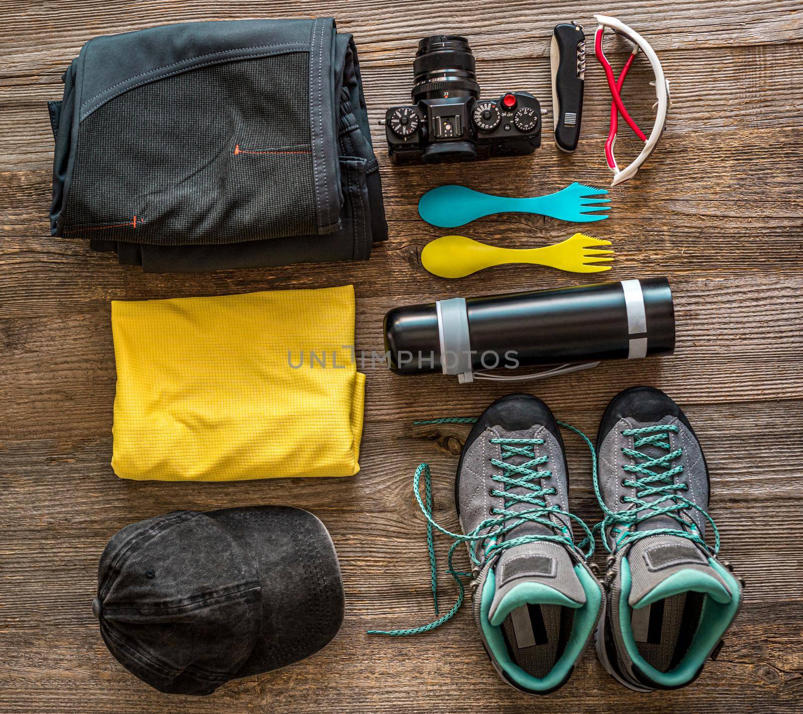 Hiking accessories on wooden background, view from top