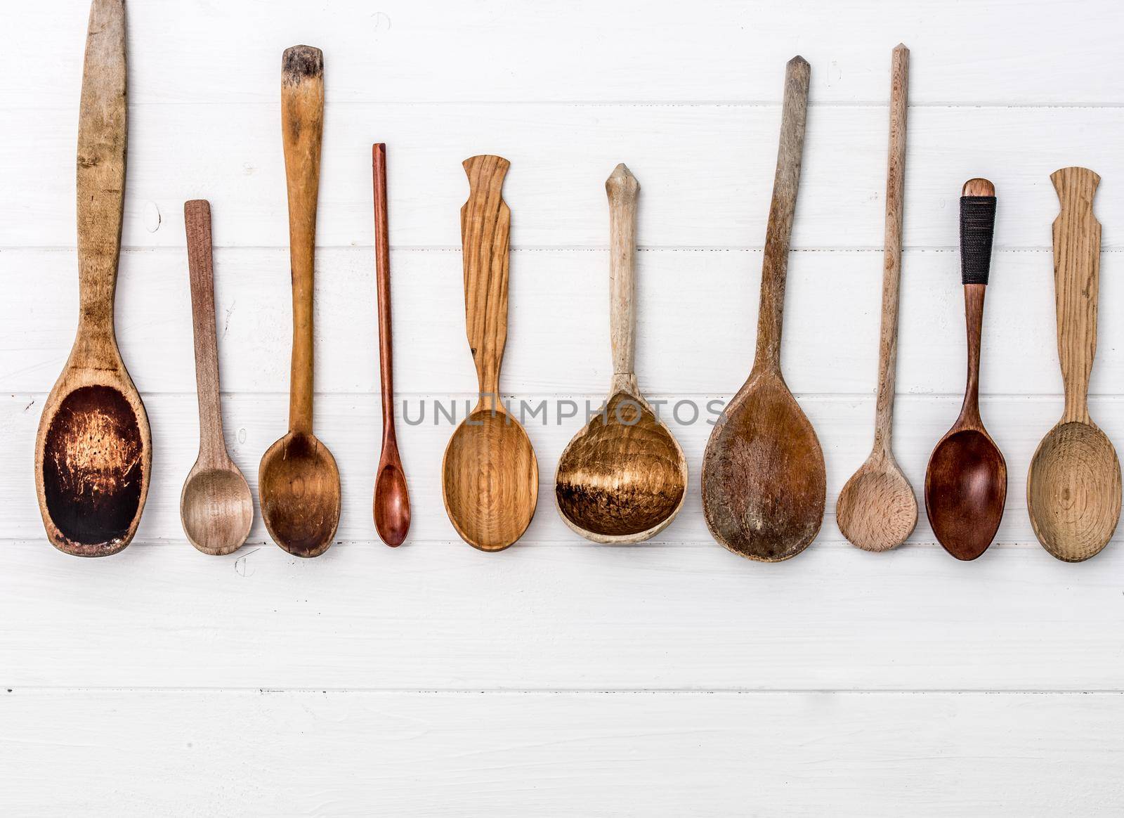 Hand-carved wooden spoons on white wooden background. Wooden kitchenware. Place for text, copyspace. Top view