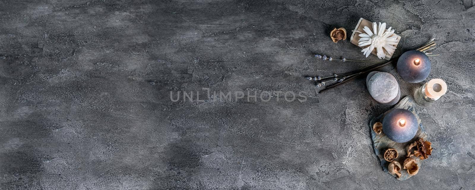 Spa compostion with candles, handmade soap and purple lavender flowers on grey background, top view with space for text.