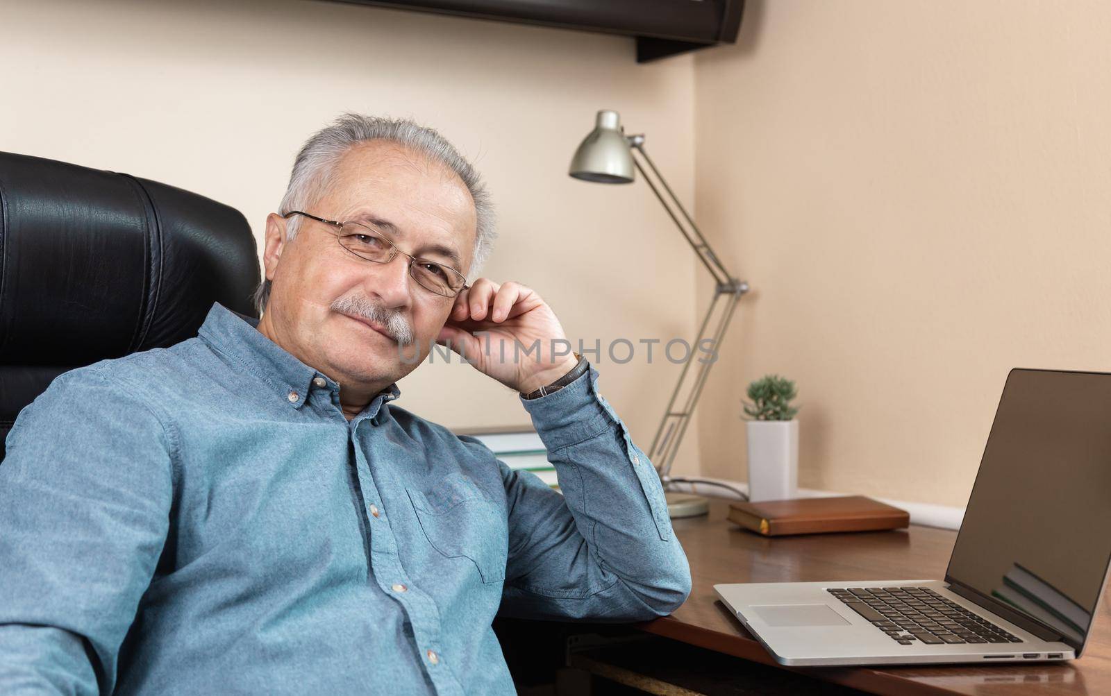 Senior businessman work at home. An elderly man in glasses is working remotely using a laptop. Remote work during coronovirus concept