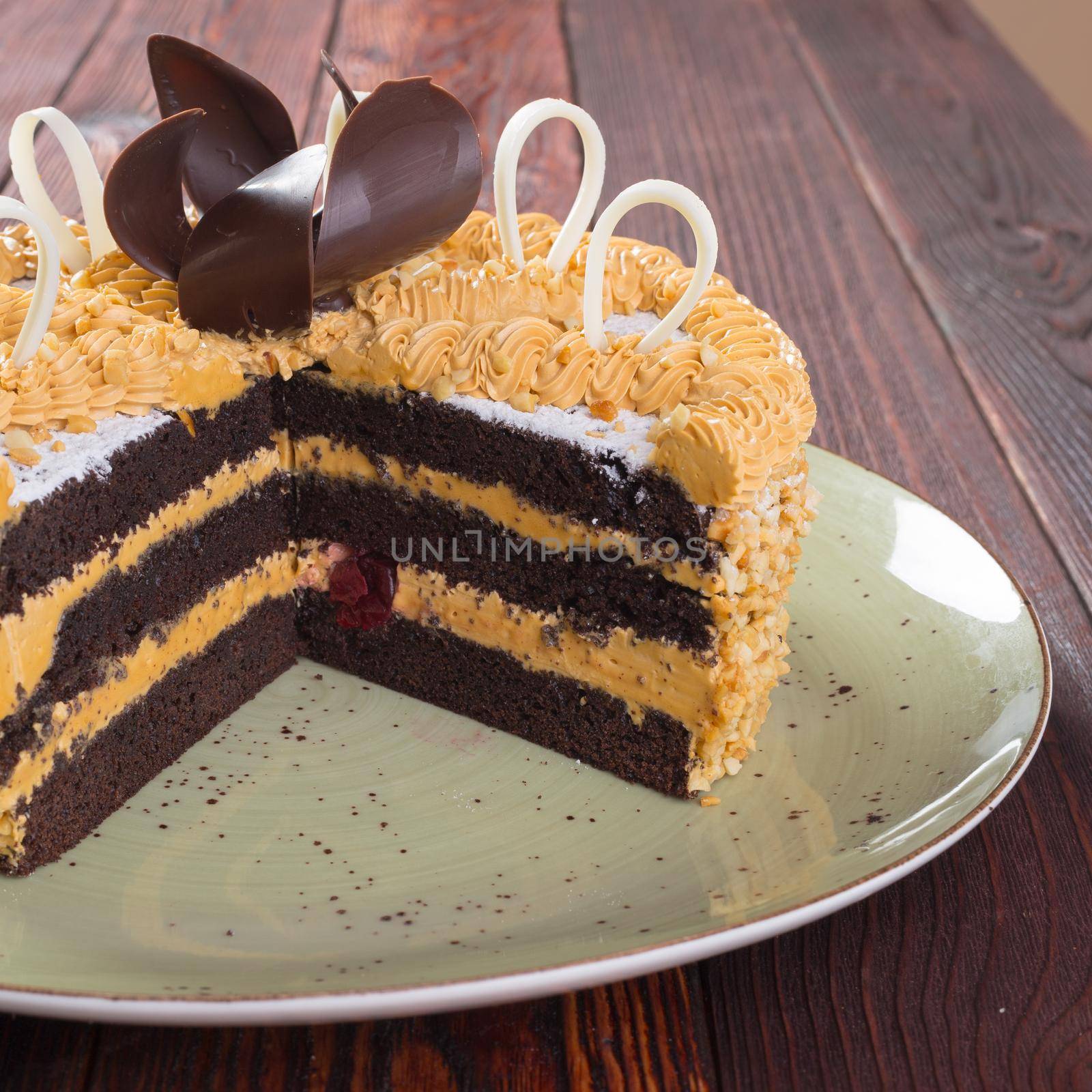 Cut caramel cake on plate on wooden table close up