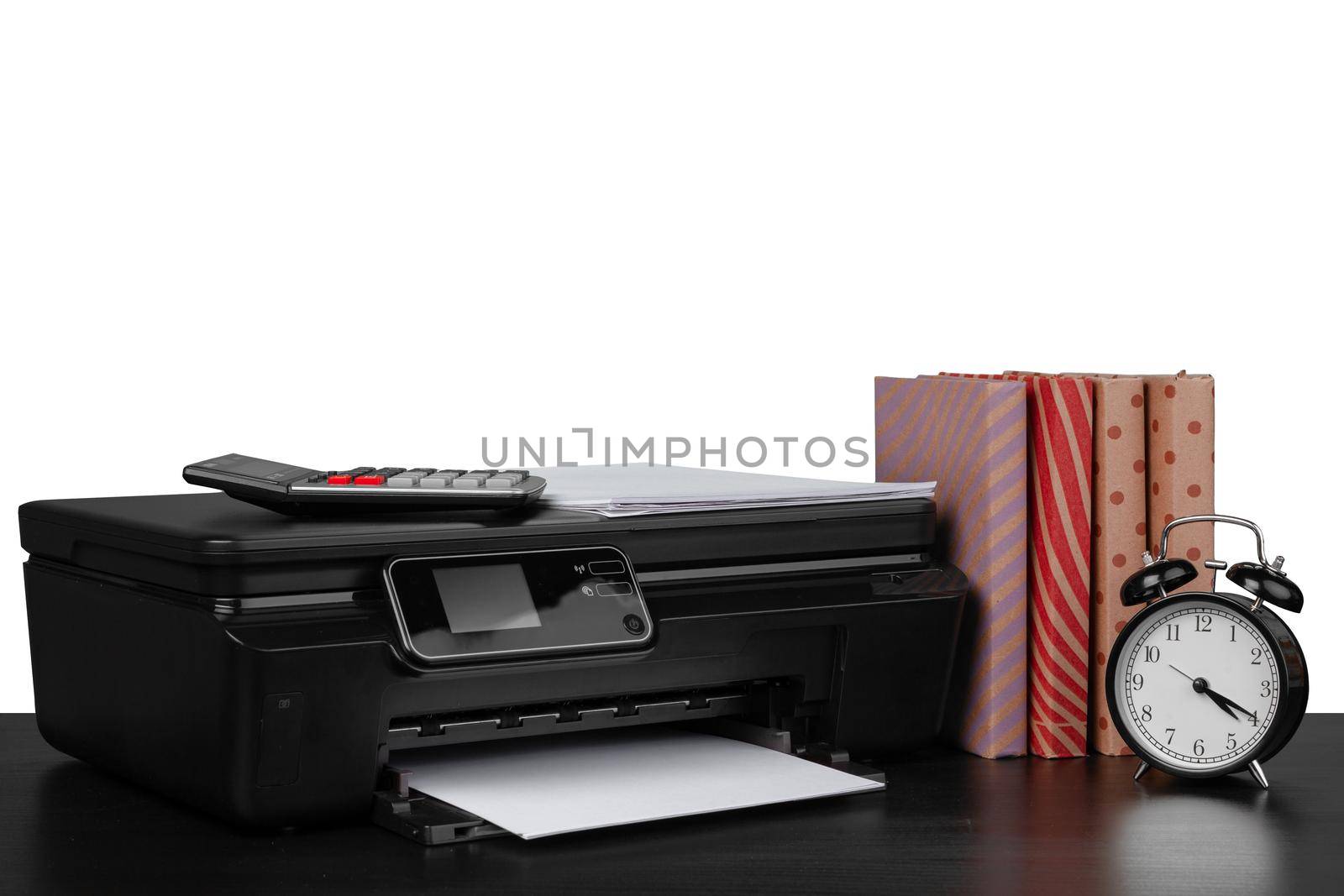 Printer and stack of books on black table against white background, close up