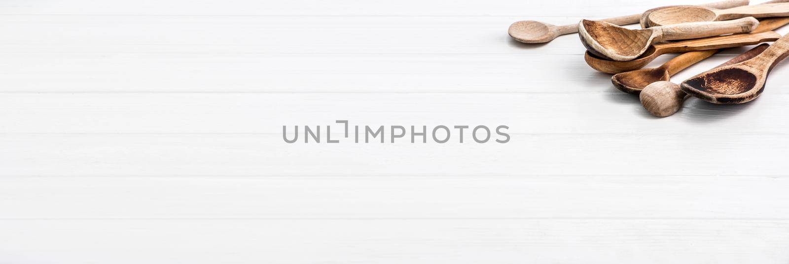 Big wooden natural spoons on white wooden background with free space for text, copyspace