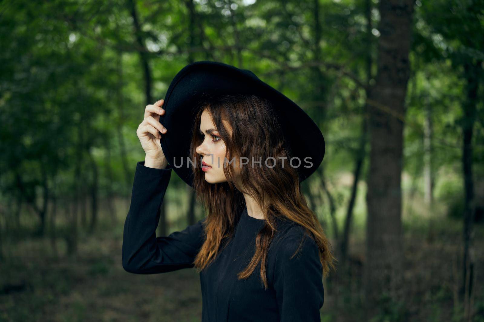 woman witch in black hat in the forest posing fantasy. High quality photo