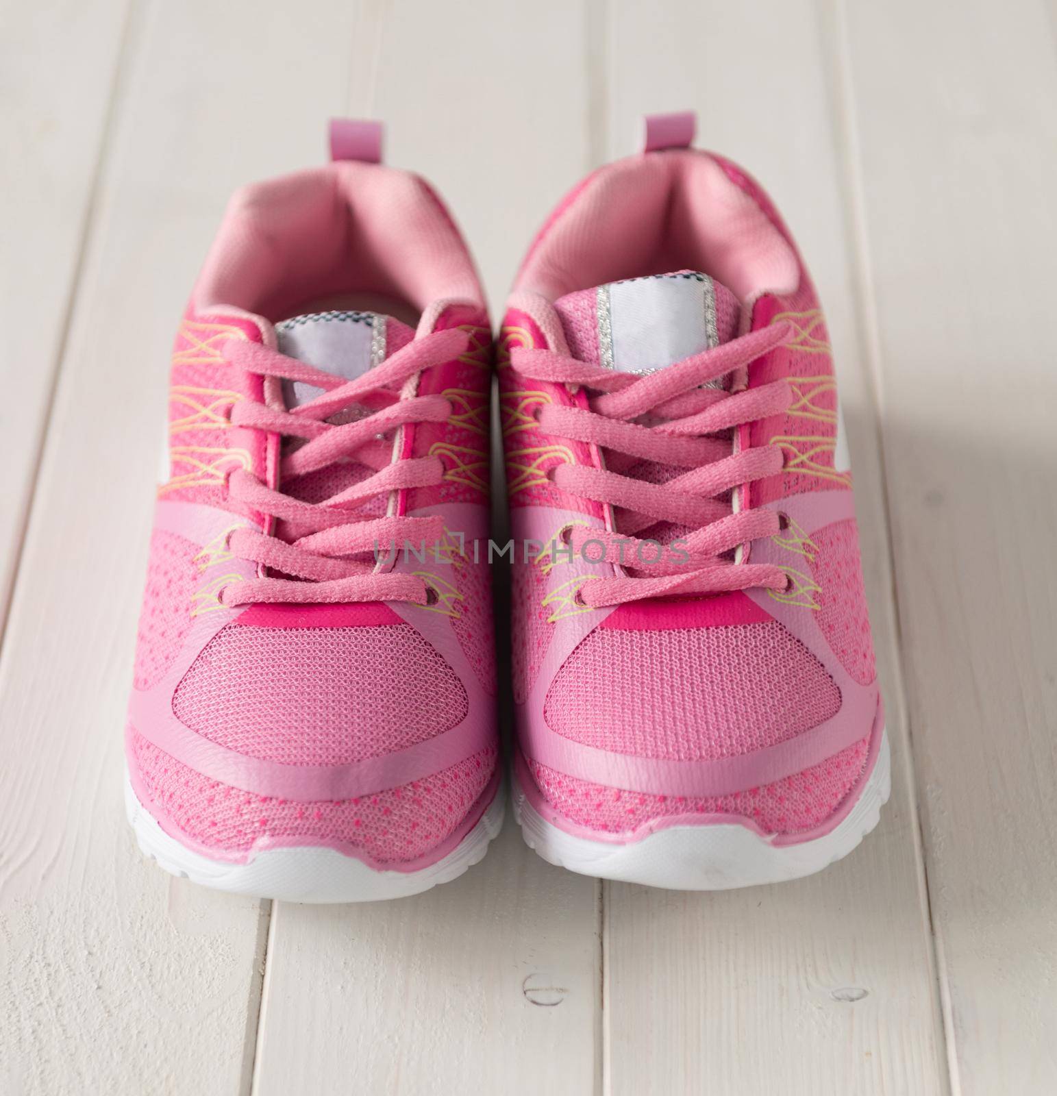 lovely tiny pink sneackers for little girl on white wooden background