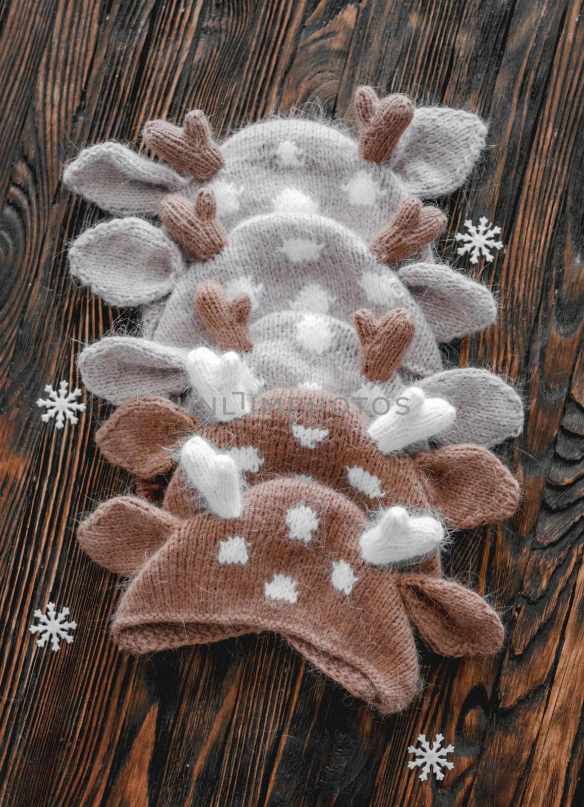 Knitted newborn hats for infant Christmas studio photoshoot on wooden background closeup