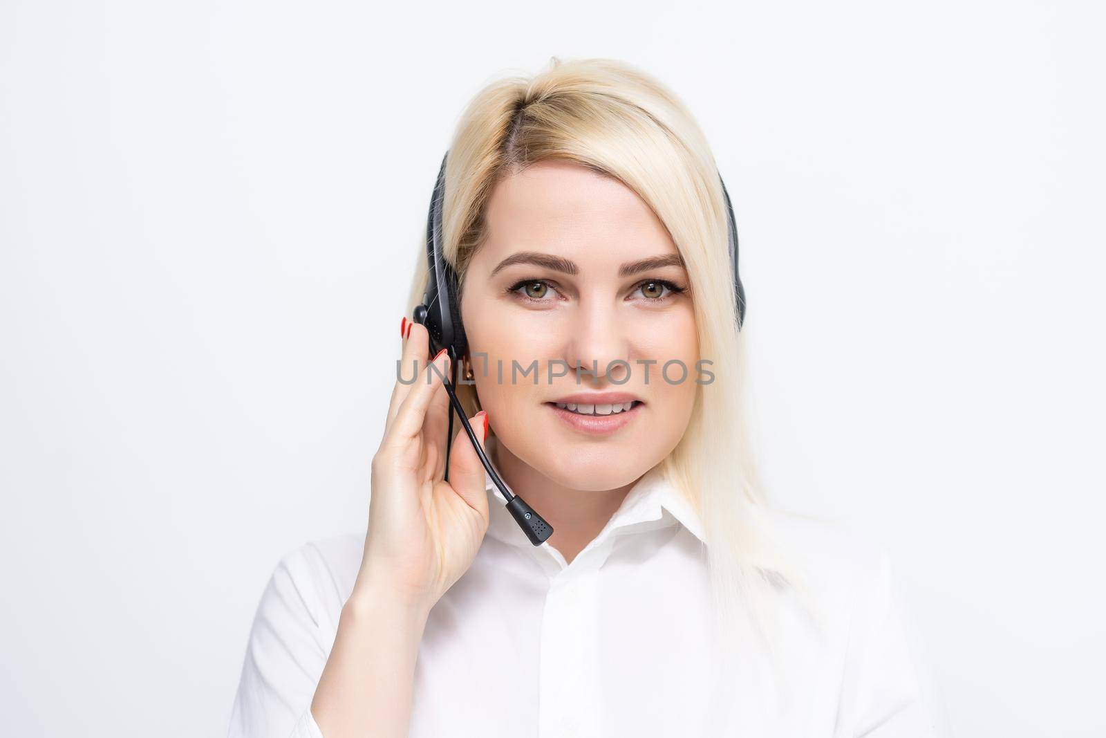 Portrait of cheerful customer support female phone operator in headset, against white brick wall background. Consulting and assistance service call center.