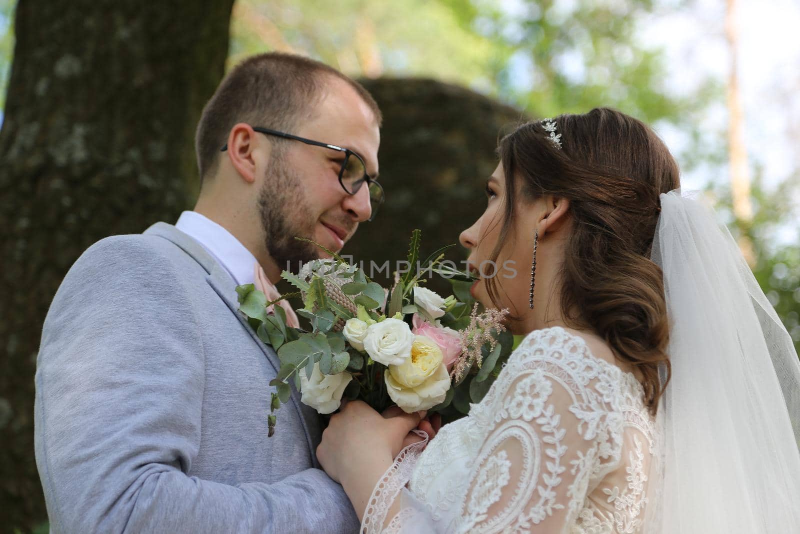 Wedding photo of the bride and groom in a gray-pink color on nature in the forest and rocks