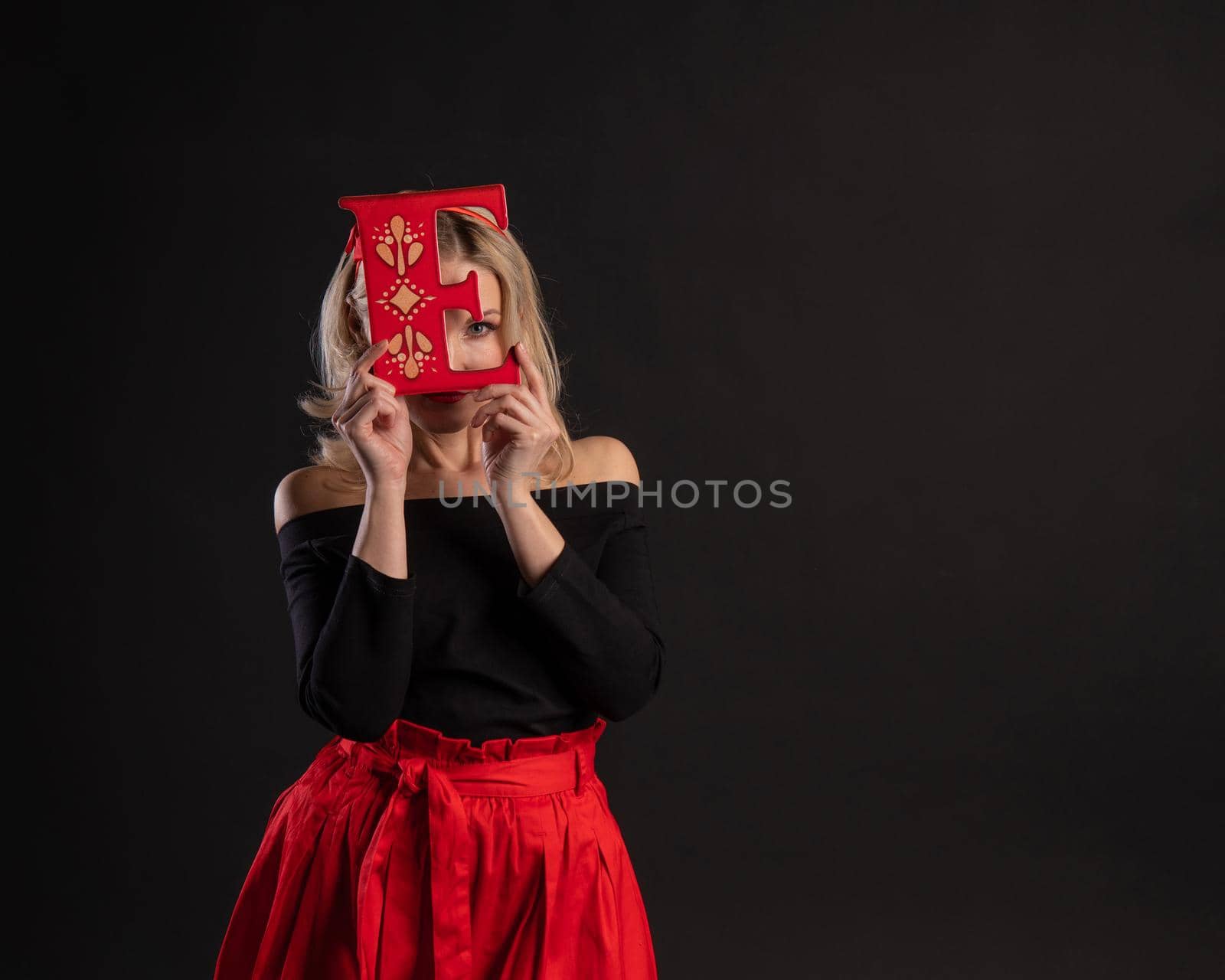 A girl holds the letters of the word LOVE symbol, Valentine's day design, married hearts on the floor . the formula . copy space festive, black in red dress girl, barefoot by 89167702191