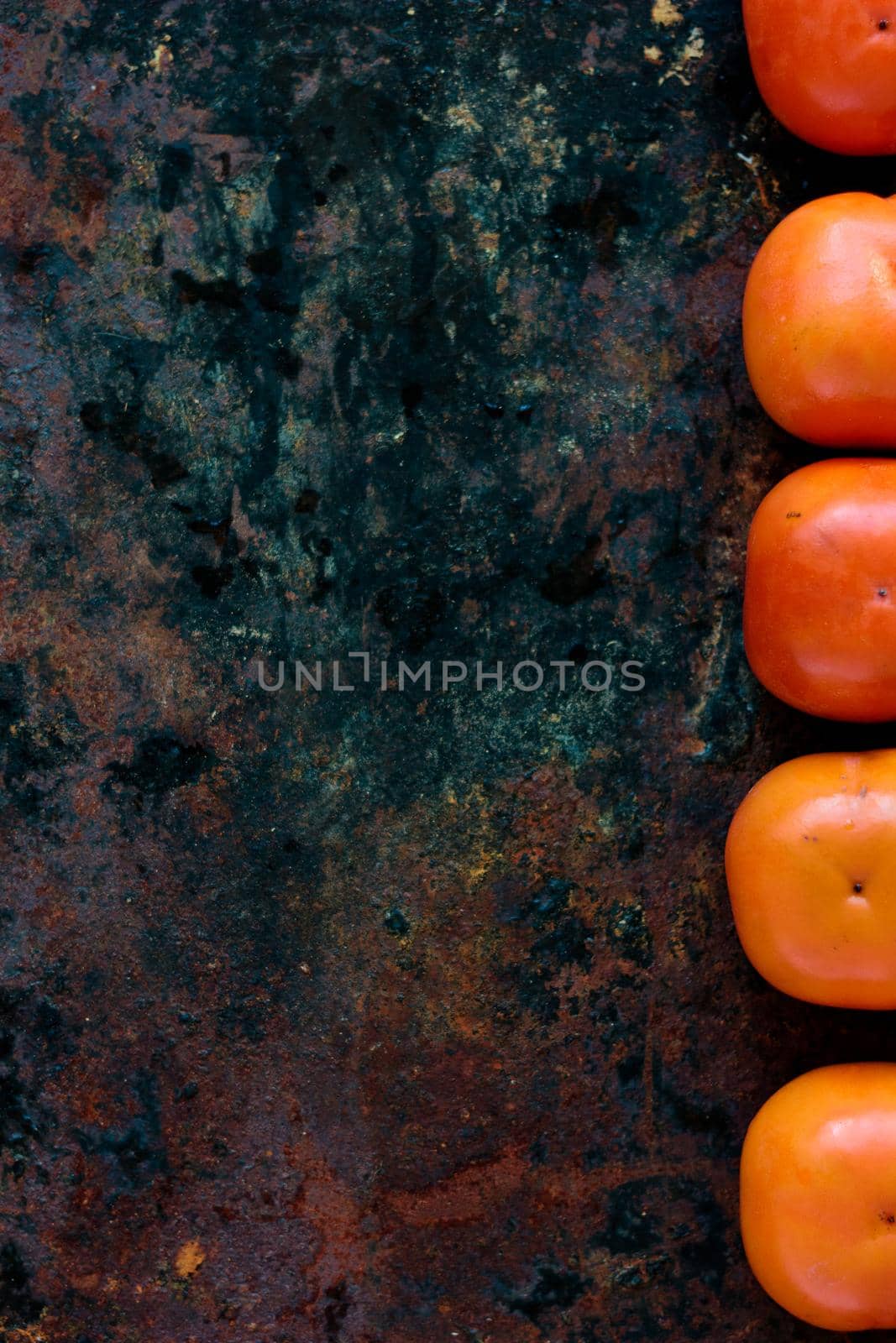 Persimmon fruits on black metal rustic background.