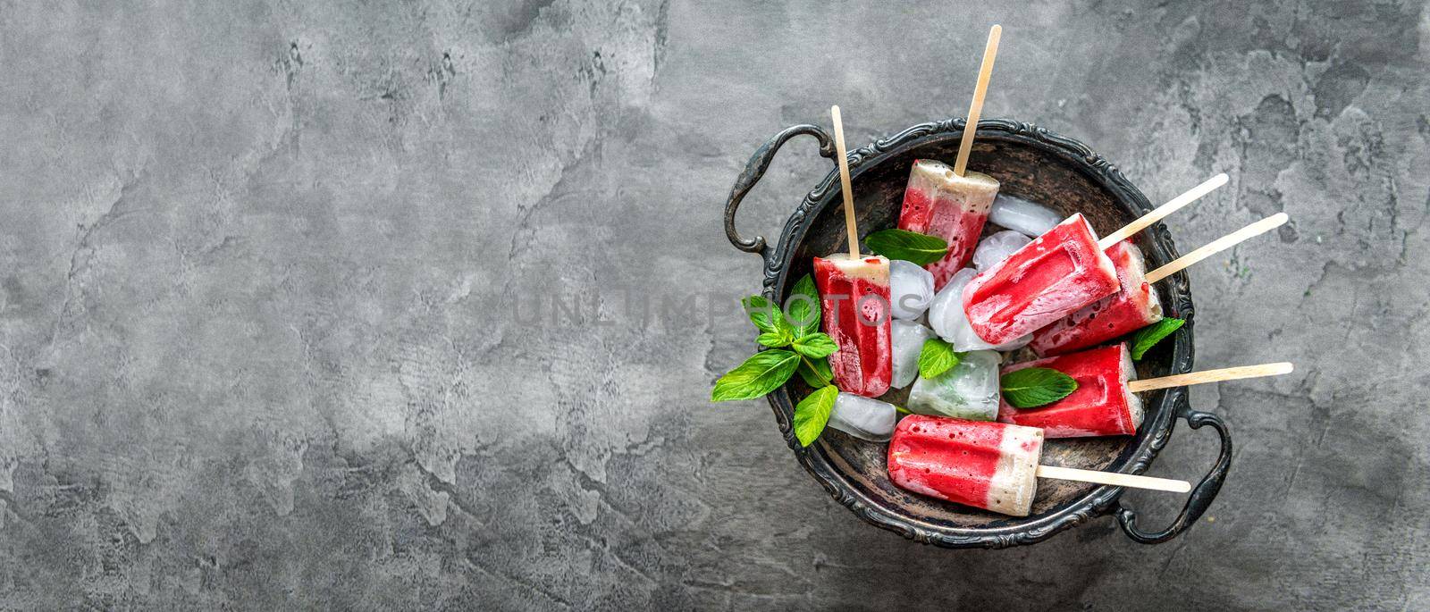 Delicious homemade ice cream with bananas and strawberries served with ice and mint leaves, topview