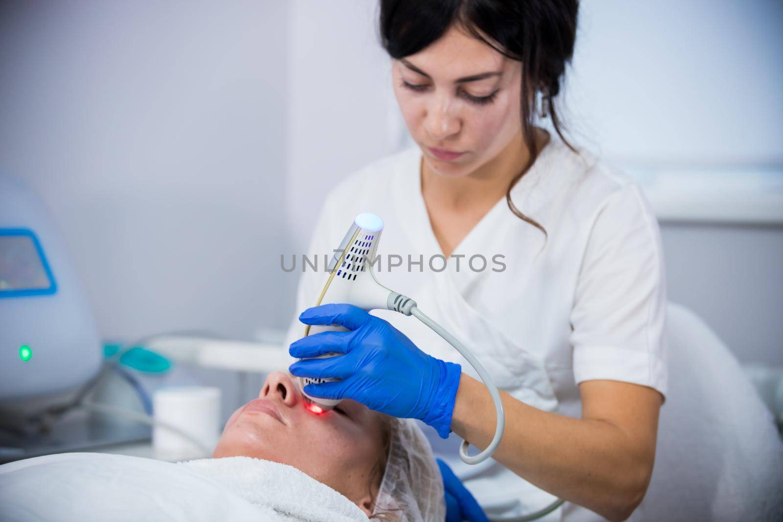 Cosmetology clinic. A client taking procedure. A woman cosmetologist working with a tool. Close up