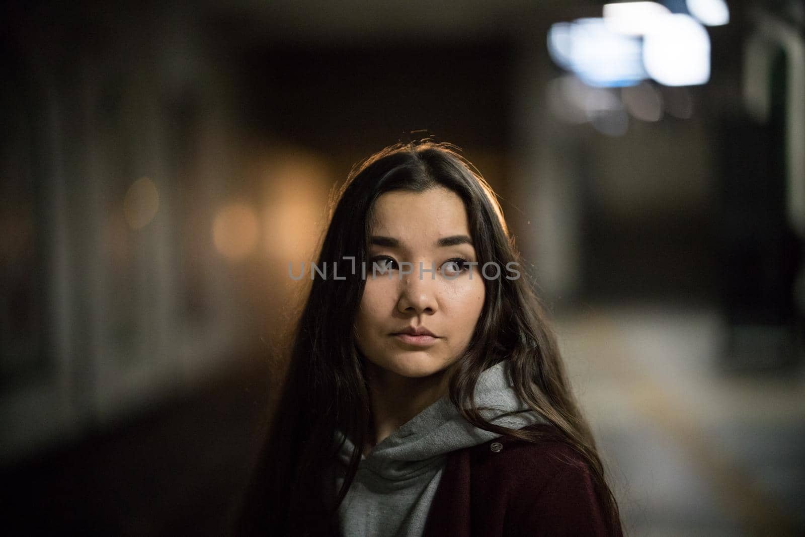 Portrait of young woman in subway. Night time. Looking to the side