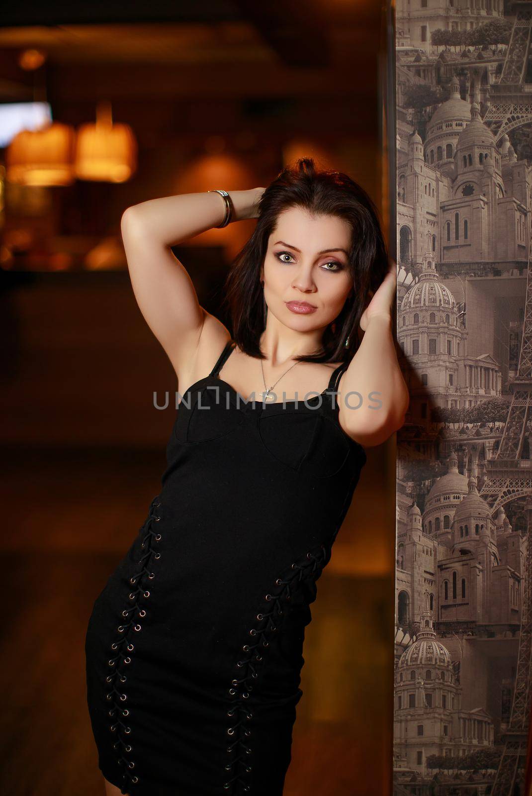 Gorgeous beauty young brunette woman in black dress posing at the bar
