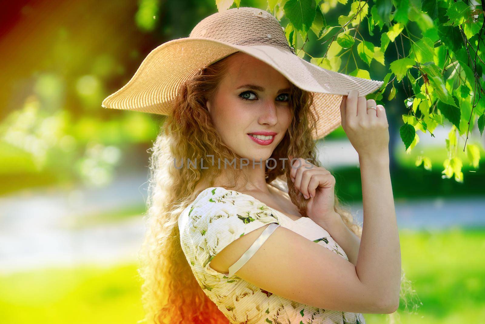 Attractive young womanwearing summer dress and hat enjoying her time outside in park