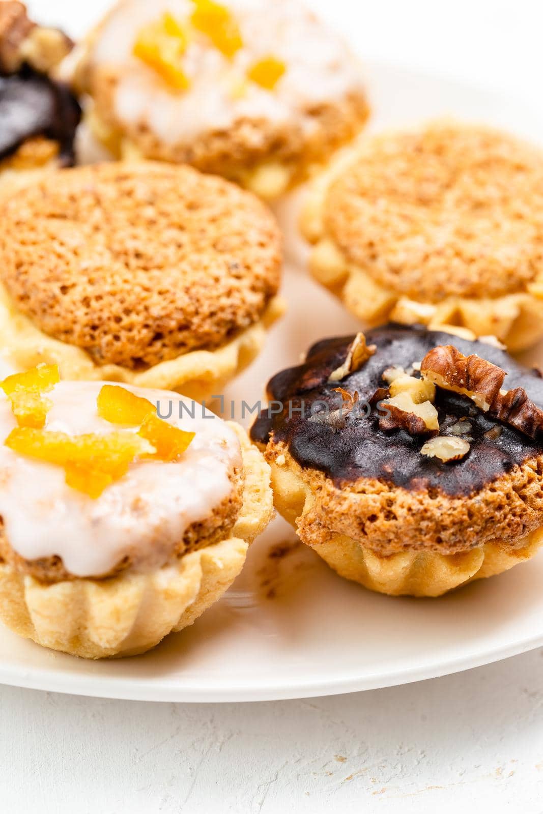Sweet mini tart served on white plate. Homemade tasty tartlets with walnuts. Tartelette close up