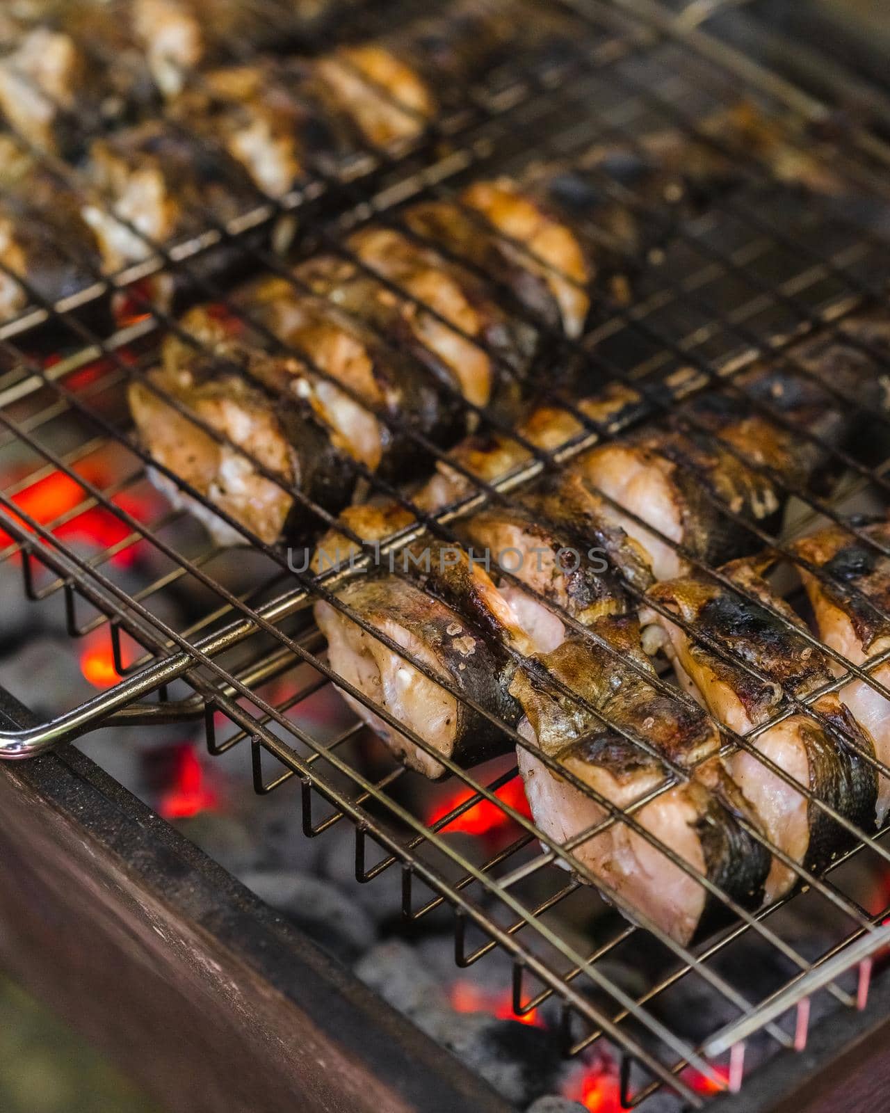 Fried trout fish on charcoal grill. Roasted fish pieces on fire.