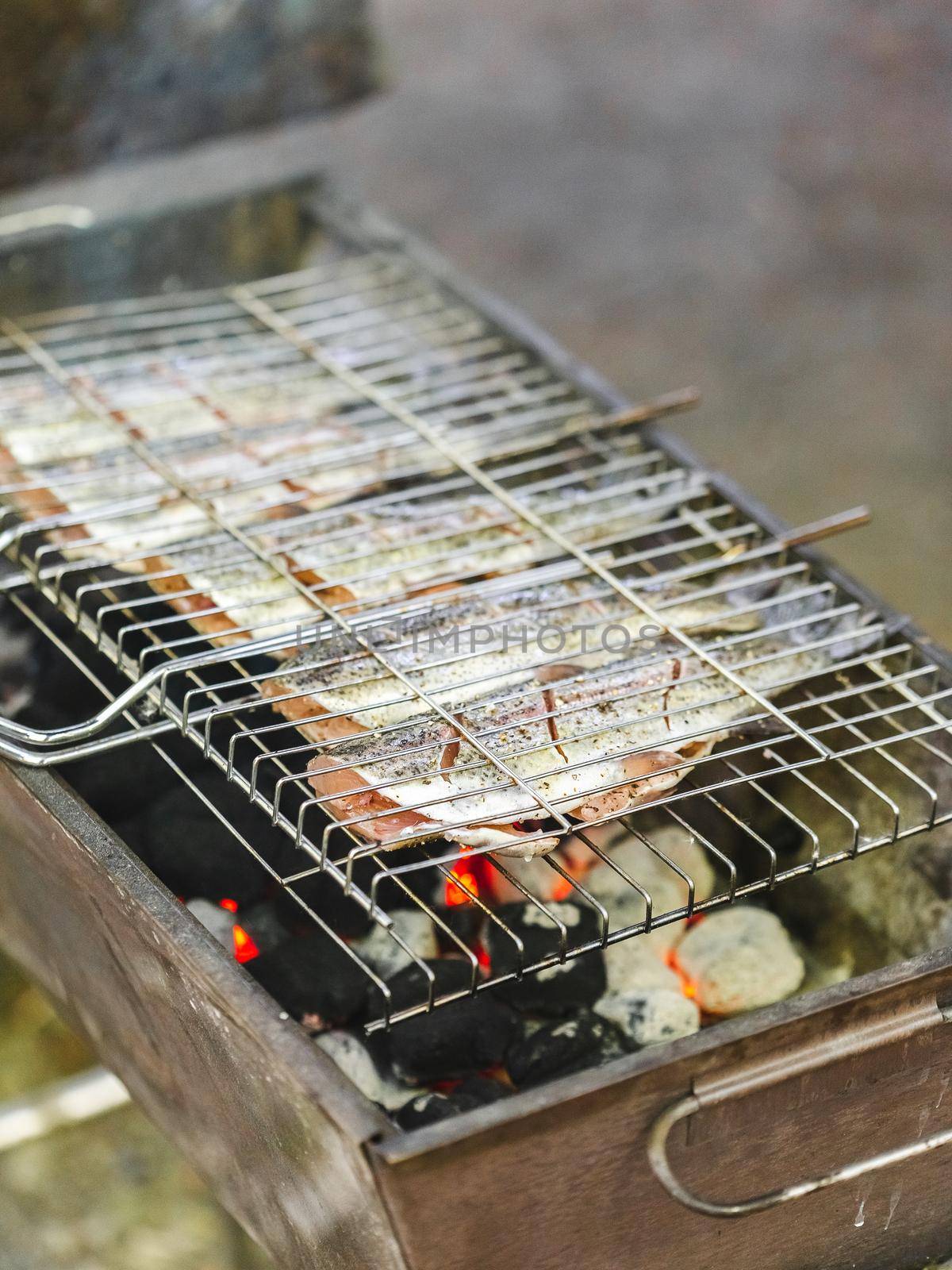 Preparing fresh trout fish on charcoal grill for Summer picnic party