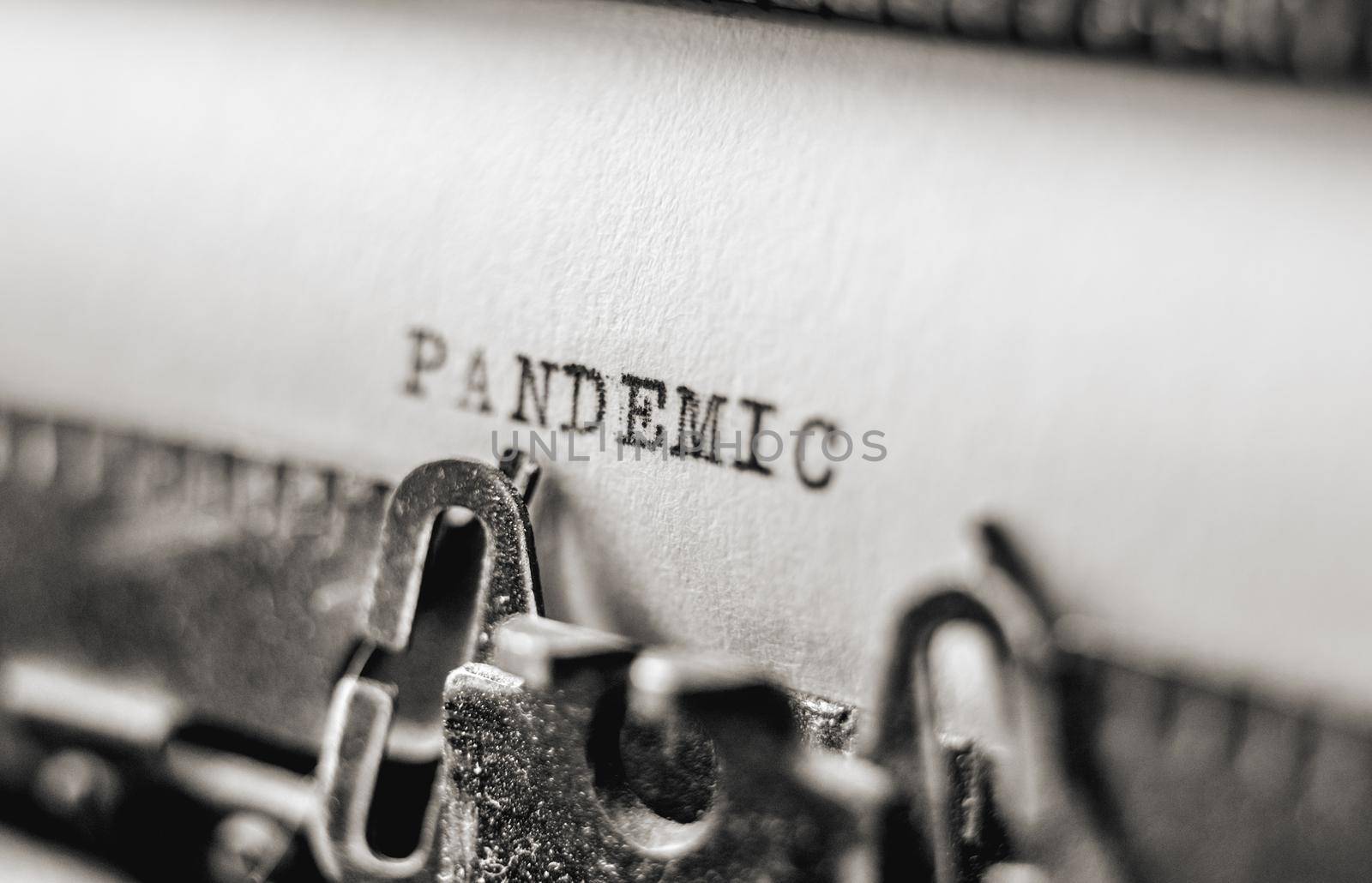 Text Pandemic printed with black inks on old white paper on retro typewriter with typographic font