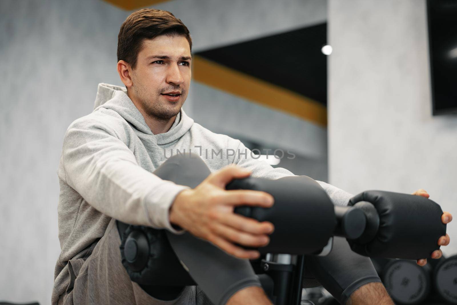 Young athlete doing abs exercises workout in modern gym, close up
