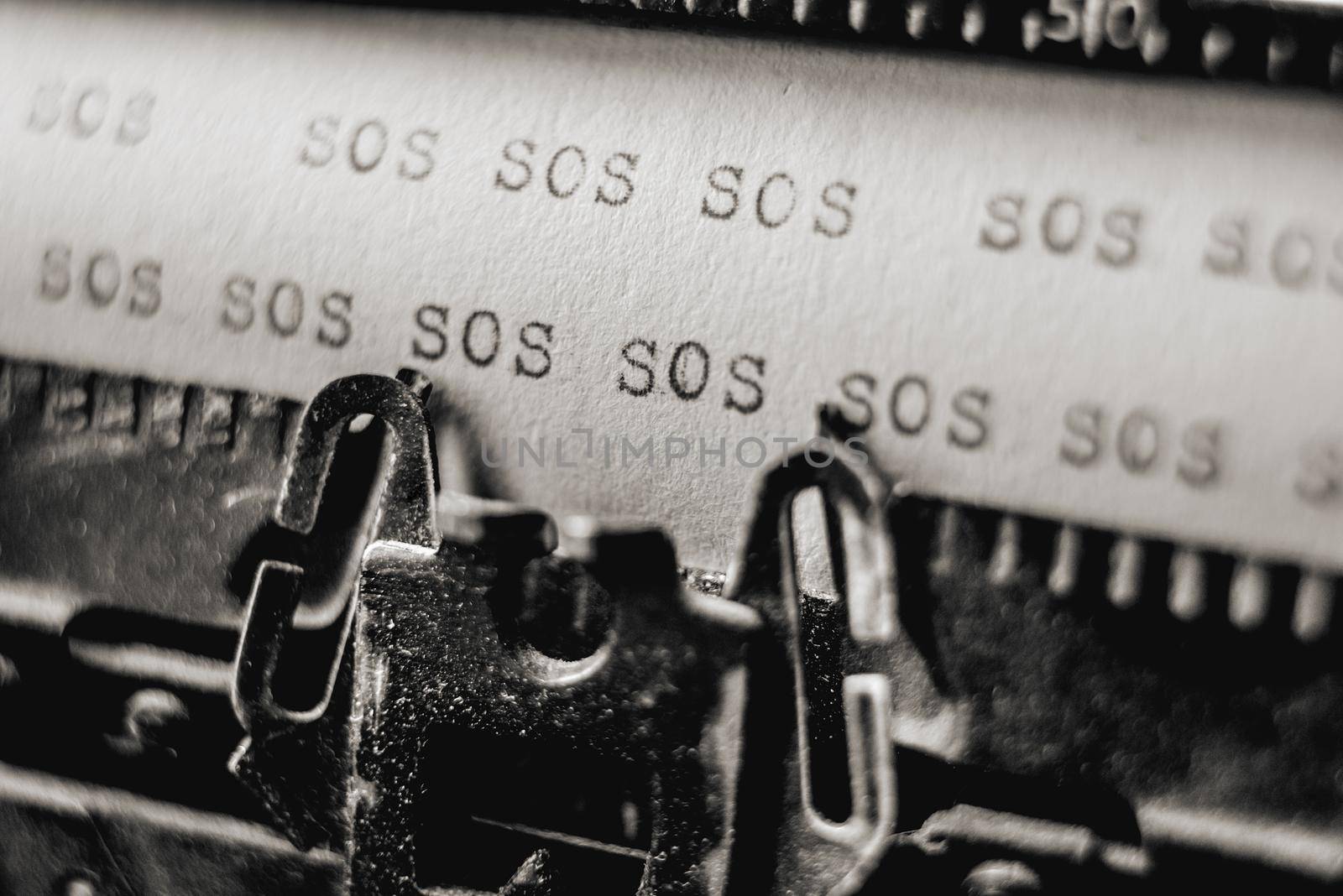 Text SOS printed many times on white paper using retro old school typewriter
