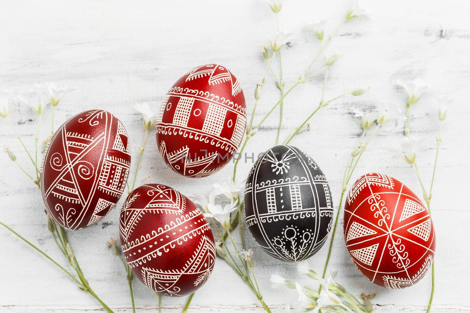 Red and black handmade Easter Pysanka eggs. Ukrainian pysanky decorated with wax-resist dyeing technique. White wooden background