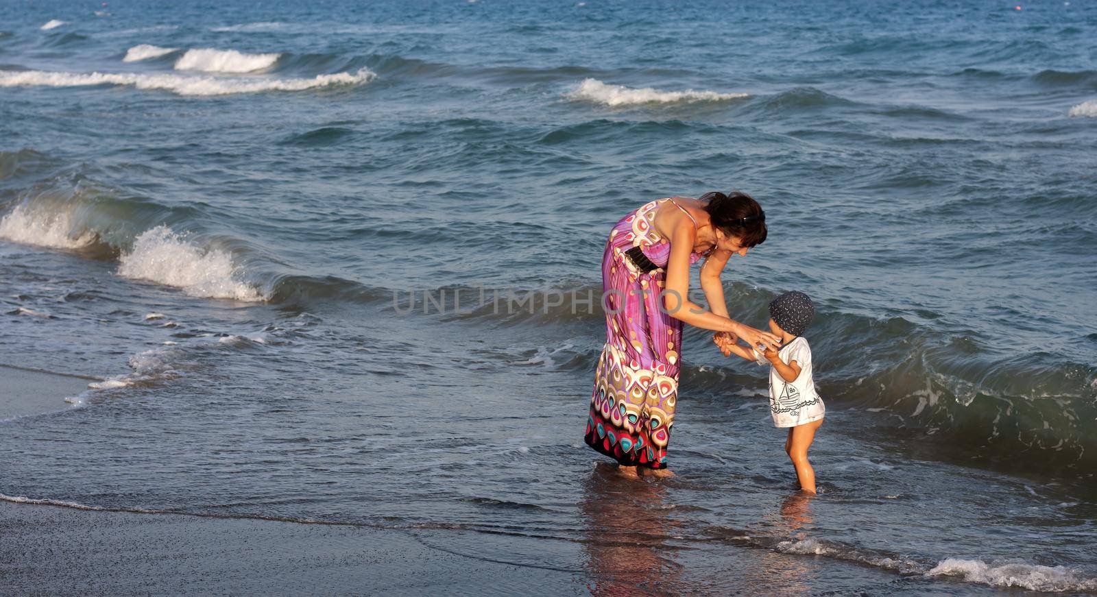 Young woman walking with her son by the sea by palinchak