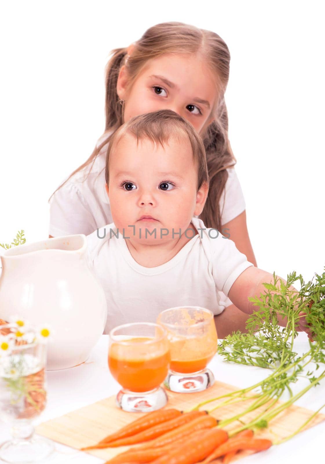 Girl and a little boy, brother and sister and carrot juice isolated on white background by aprilphoto