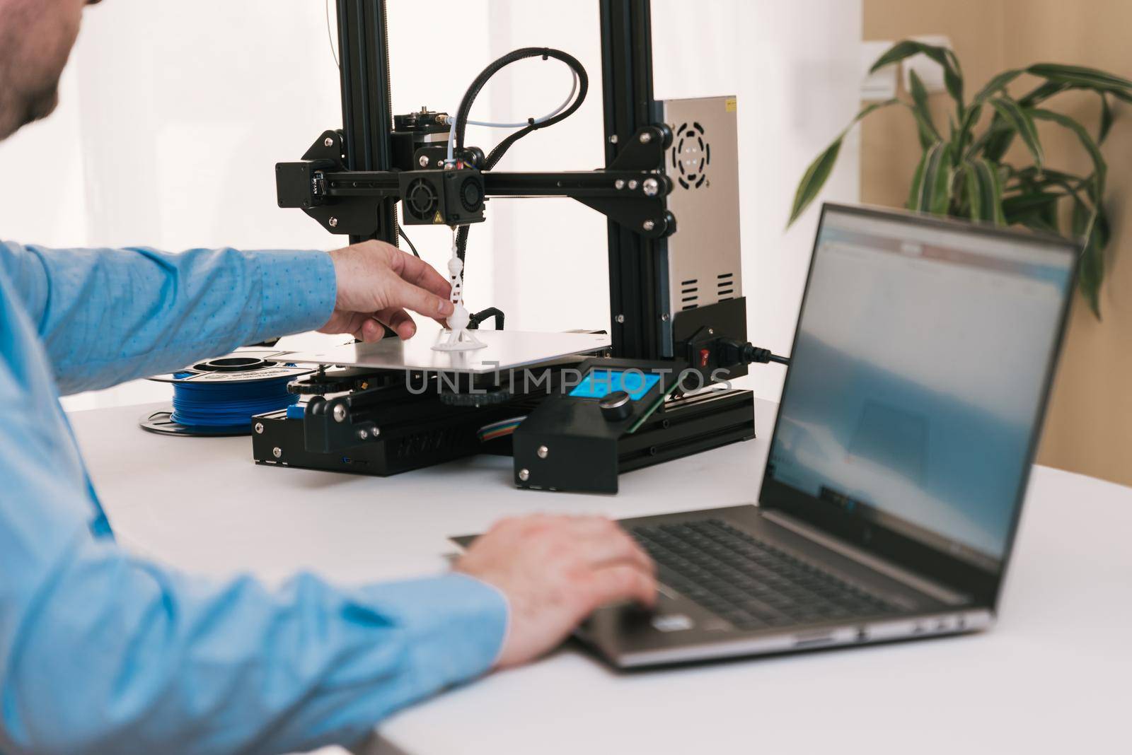 Young engineer in the lab adjusting a 3D printer's components.