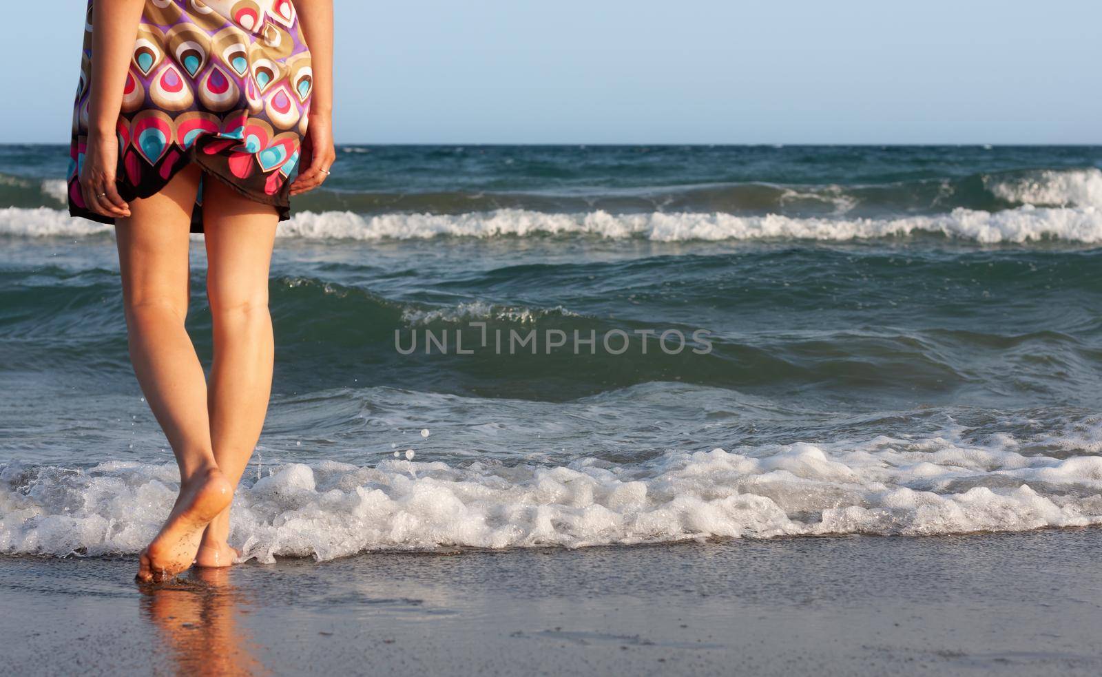 woman in a summer dress stands in the sea by palinchak