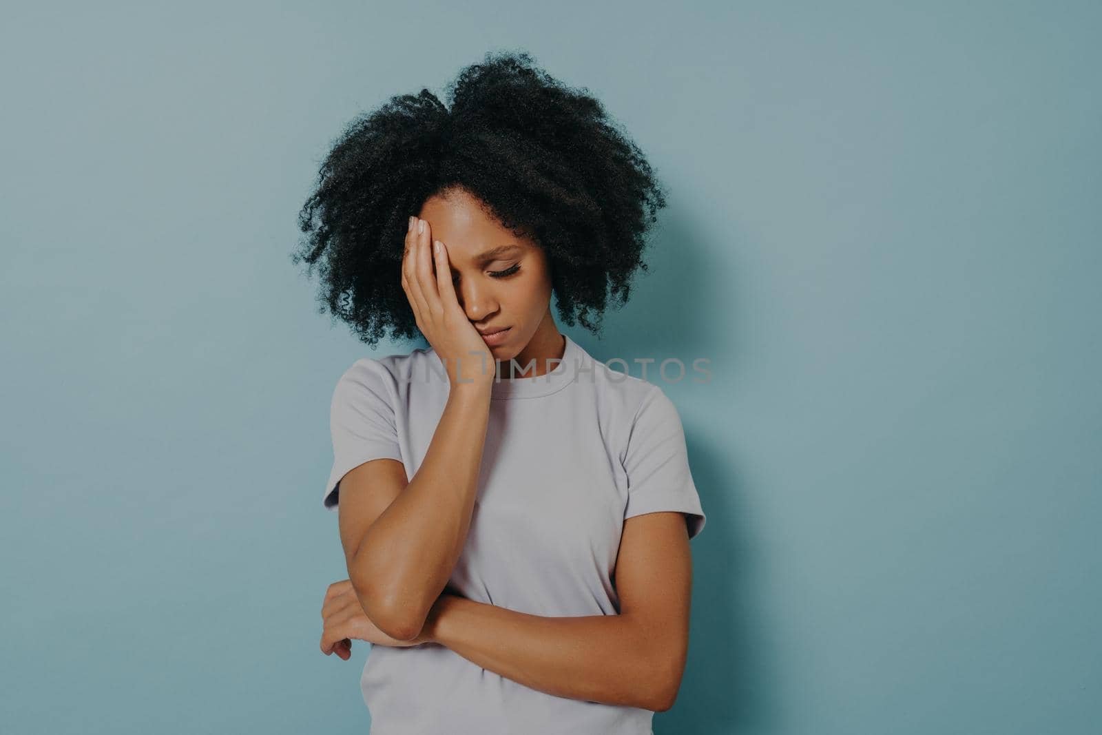 Portrait of upset African woman wearing casual clothes holding head with hand, having stressful look while suffering from migraine or headache. Unhappy female feeling frustrated, closing eyes tight
