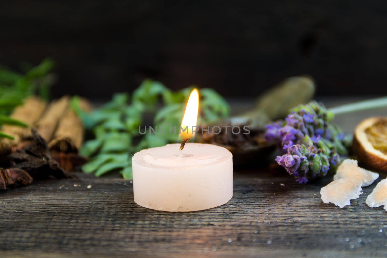 variety of flowers, herbs, candles and essences for aromatherapy, on rustic wood