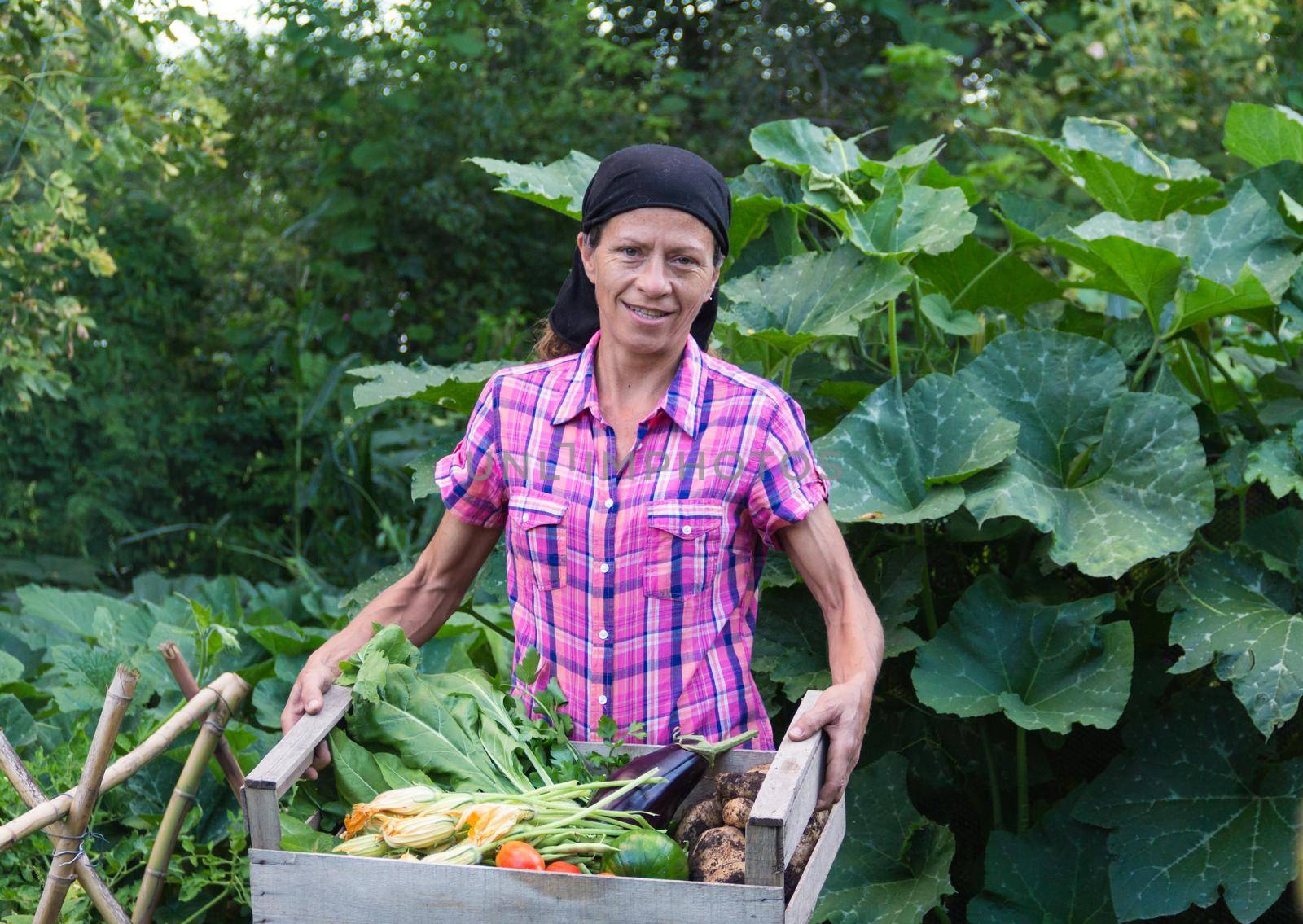 rural woman with the harvest of vegetables from the organic garden in a wooden crate