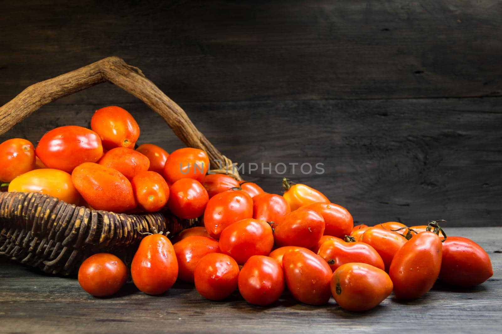 basket overflowing with pear tomatoes on rustic wood