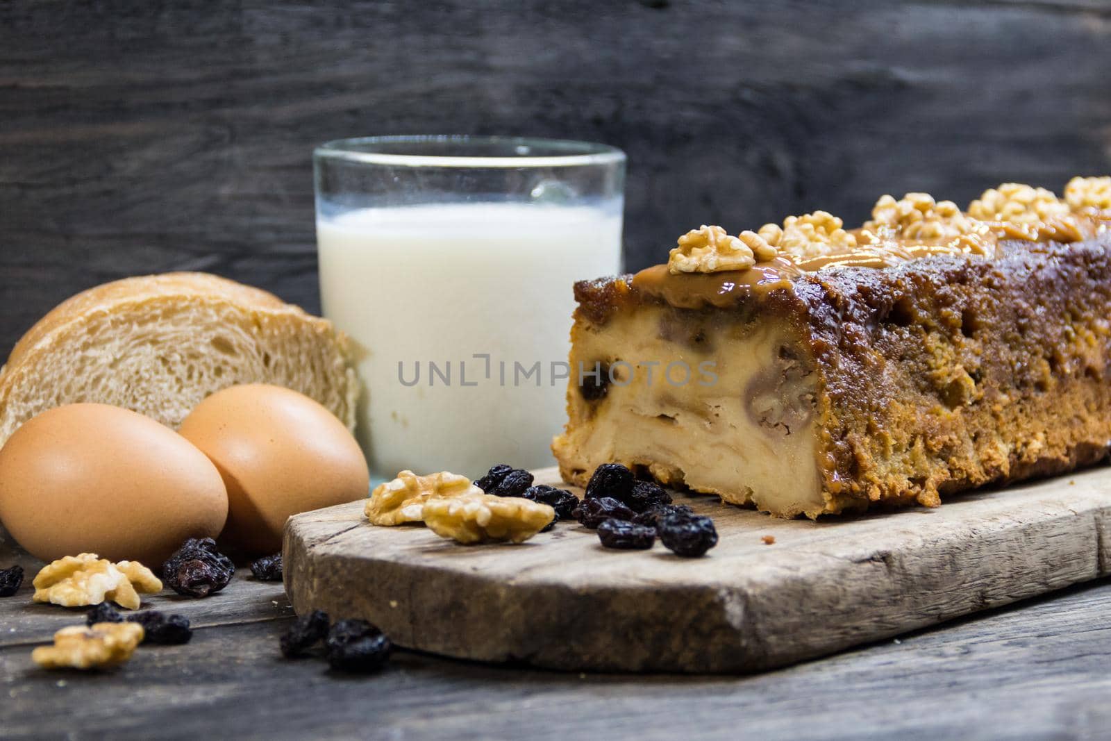 Bread pudding, made with milk, eggs, stale bread and dried fruits on rustic wooden background by GabrielaBertolini