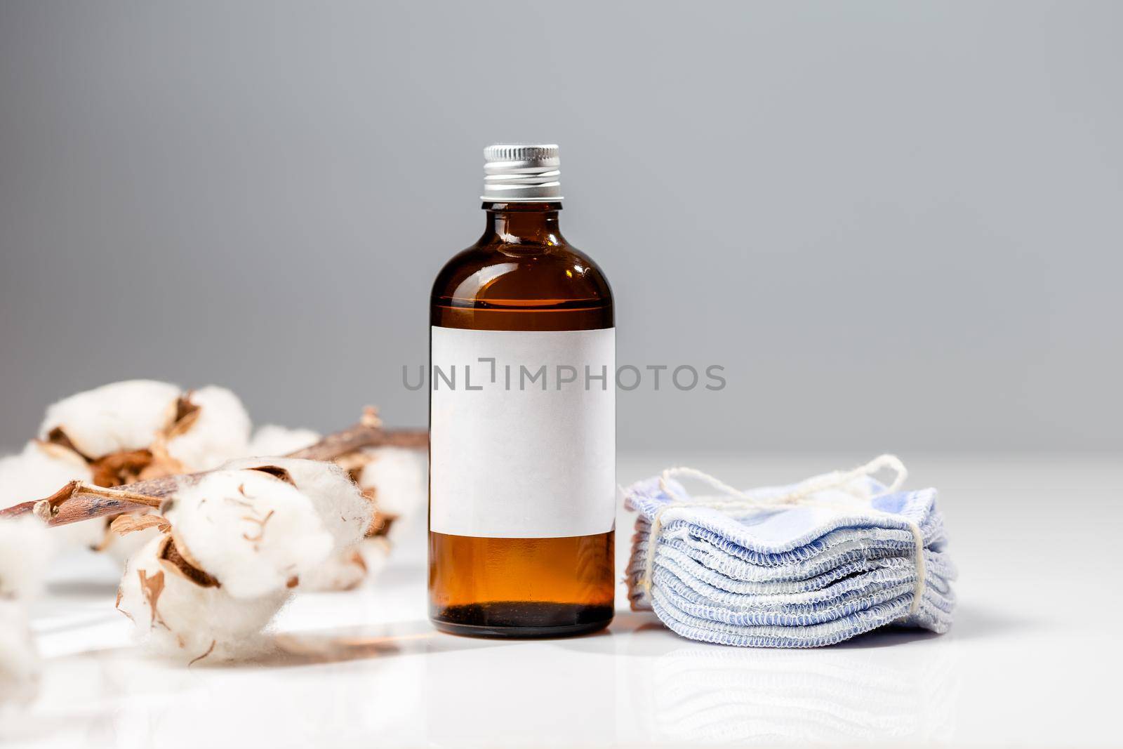 Brown glass bottle with for natural skin care toner product and stack of reusable cotton round pads. White label mock up, space for text